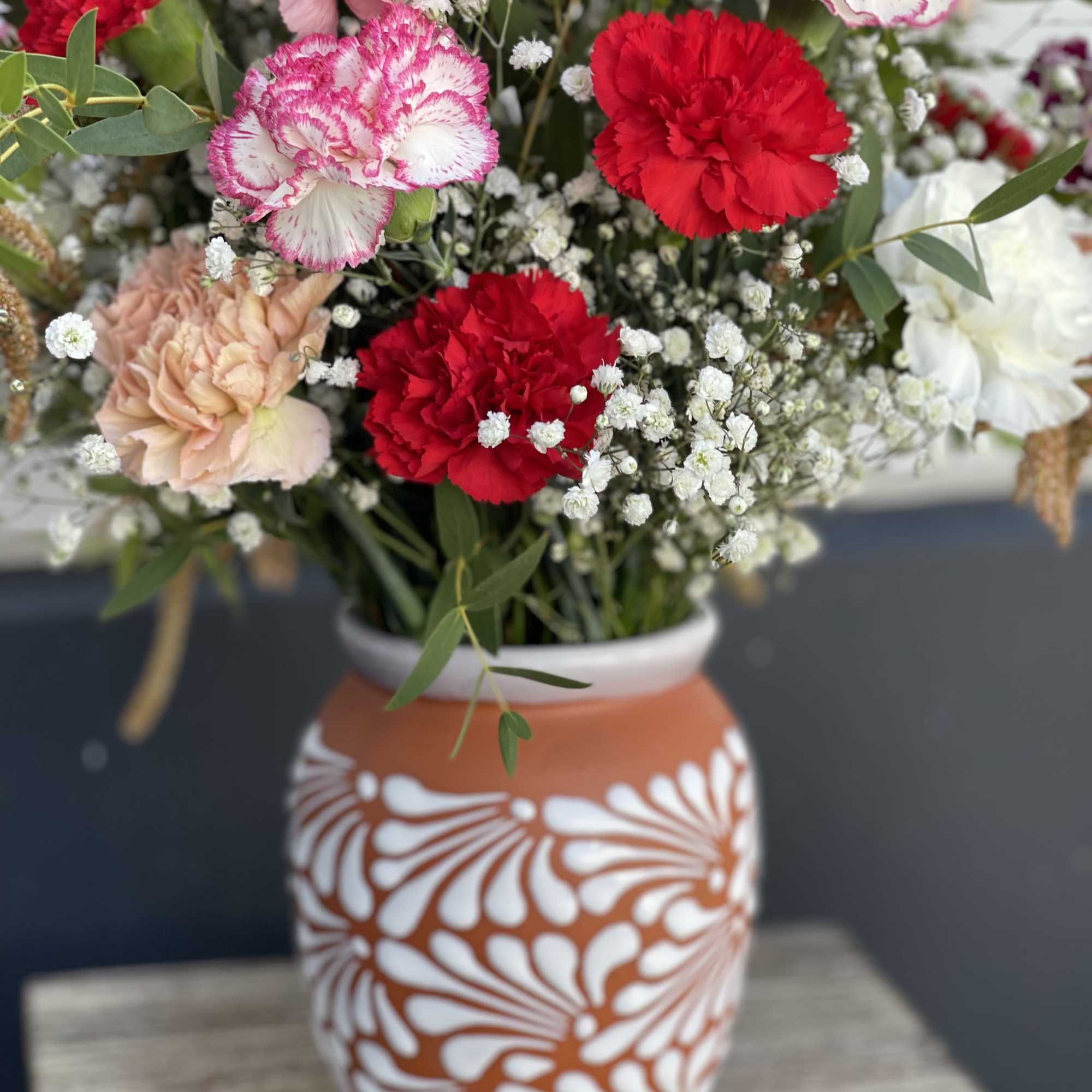 Mixed carnations and baby's breath in a patterned vase