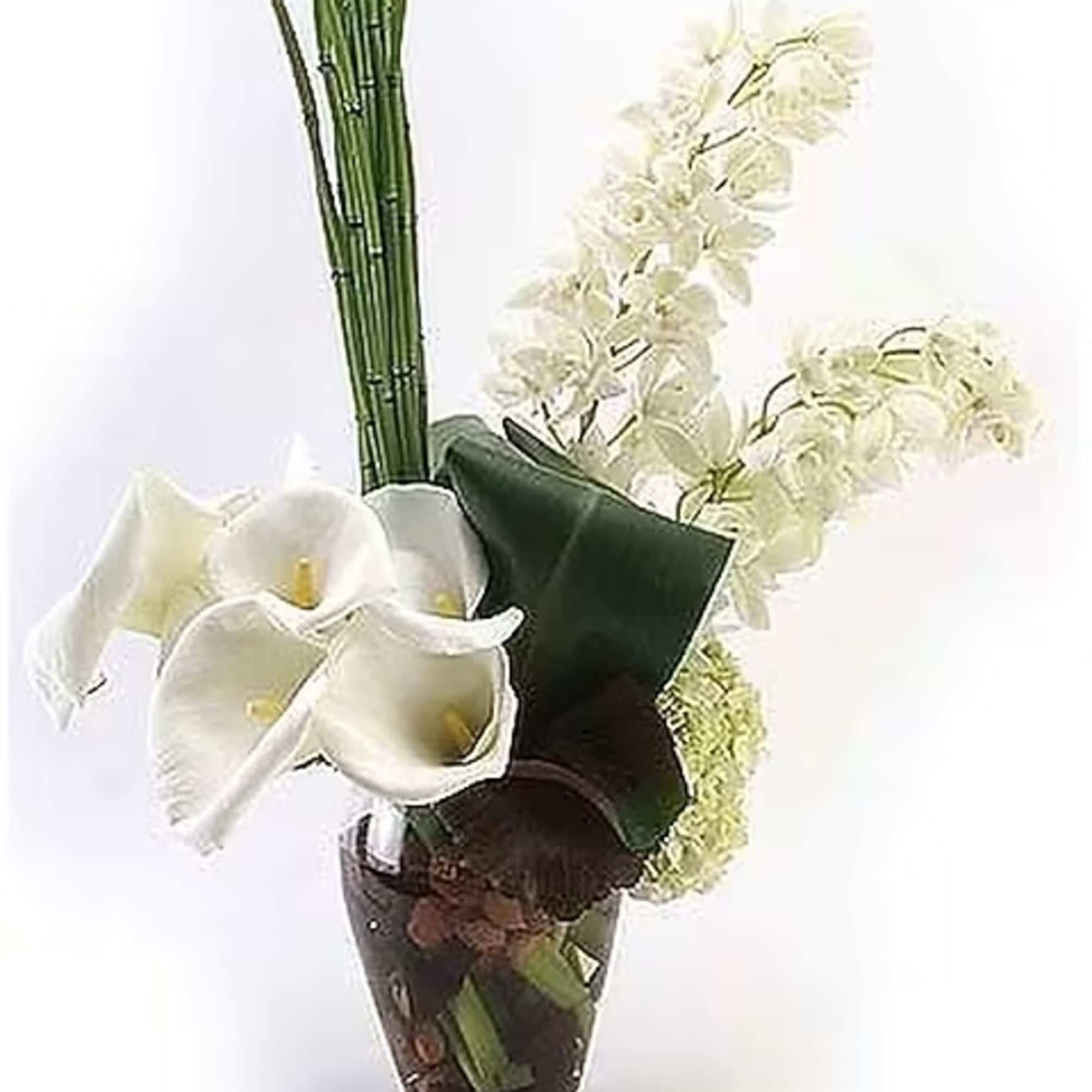 Callas and orchids in a clear glass vase arranged in a contemporary