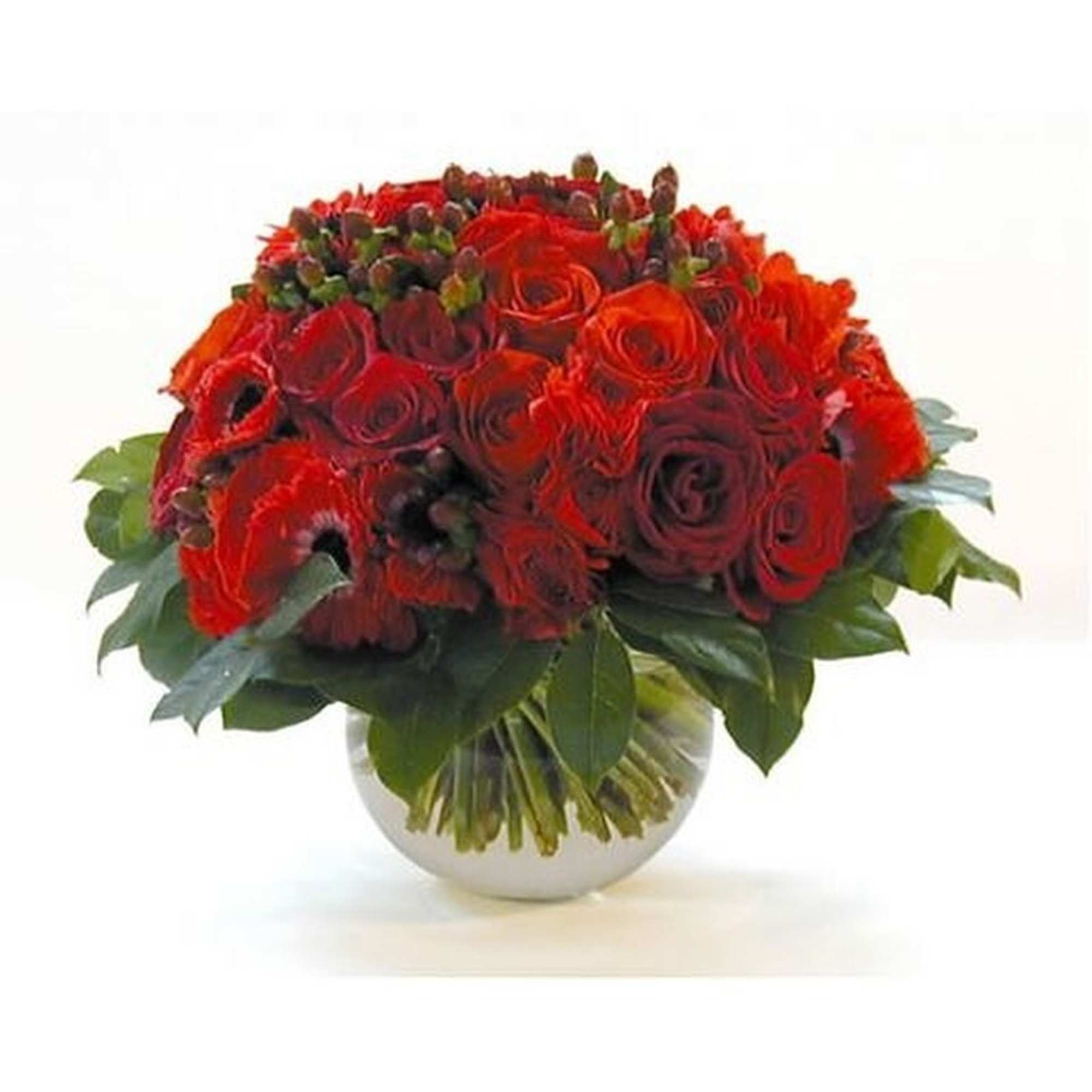 Low round arrangement of red roses in a clear glass bowl vase with a collar of glossy leaves.