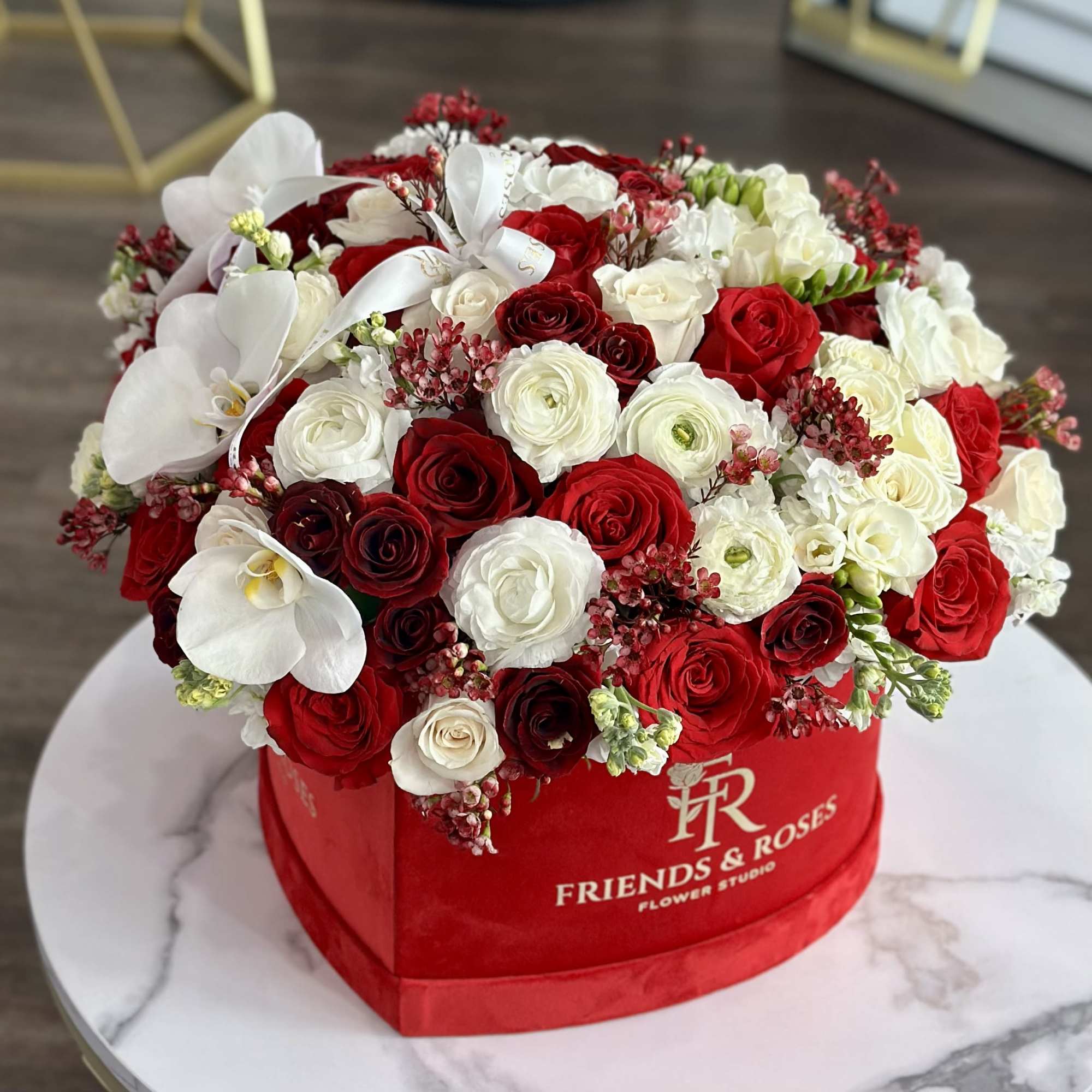 Red and white rose arrangement with white orchids in a red hat box