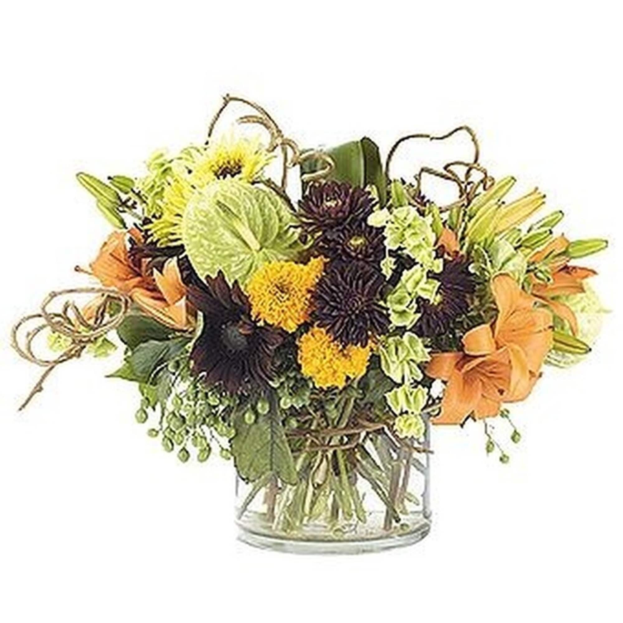 Low arrangement of orange lilies, yellow and dark blooms with green accents in a clear glass vase