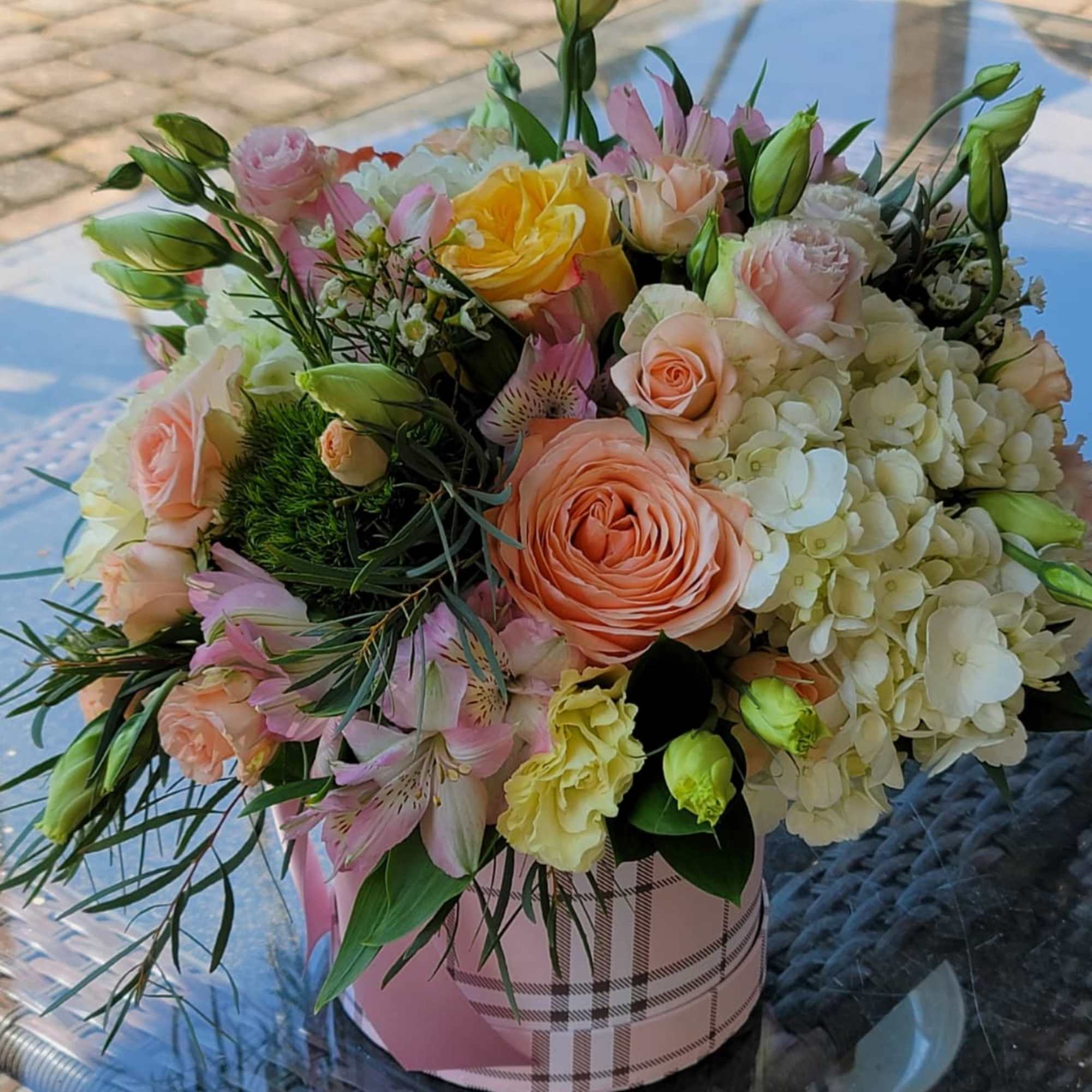 Mixed bouquet of roses, hydrangeas, and lilies in a pink hatbox