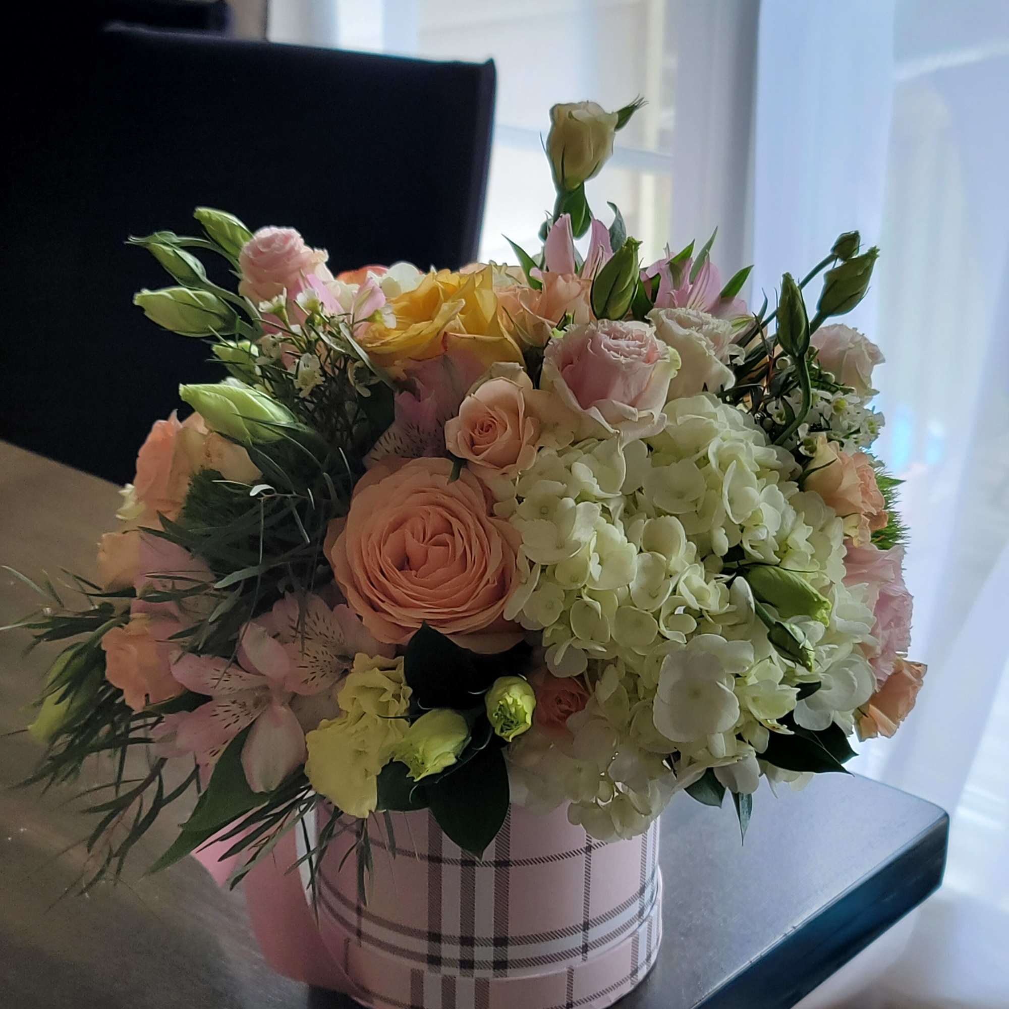Pastel bouquet of roses, hydrangeas, and alstroemeria in a plaid hat box