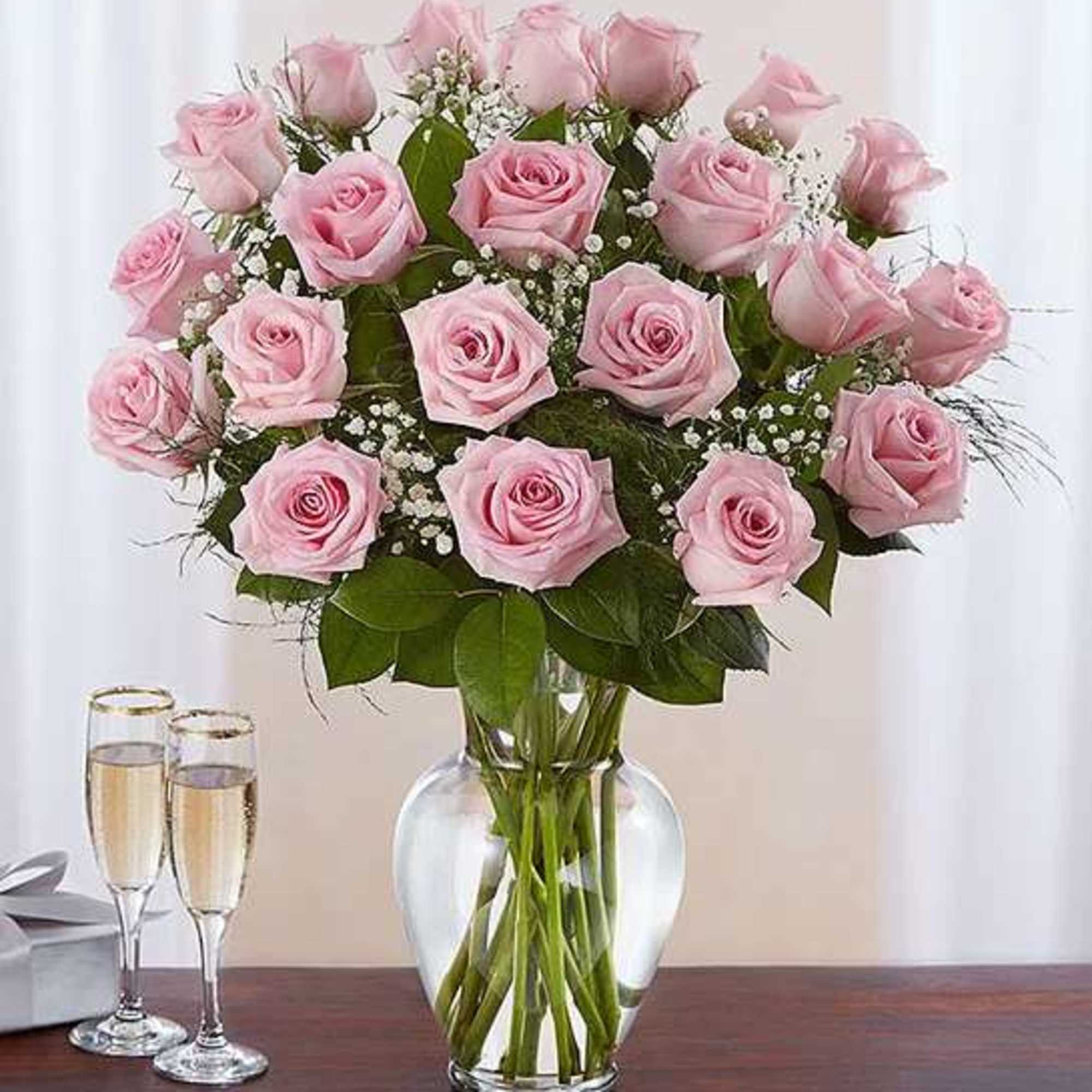 Pink roses arranged in a clear glass vase with baby's breath