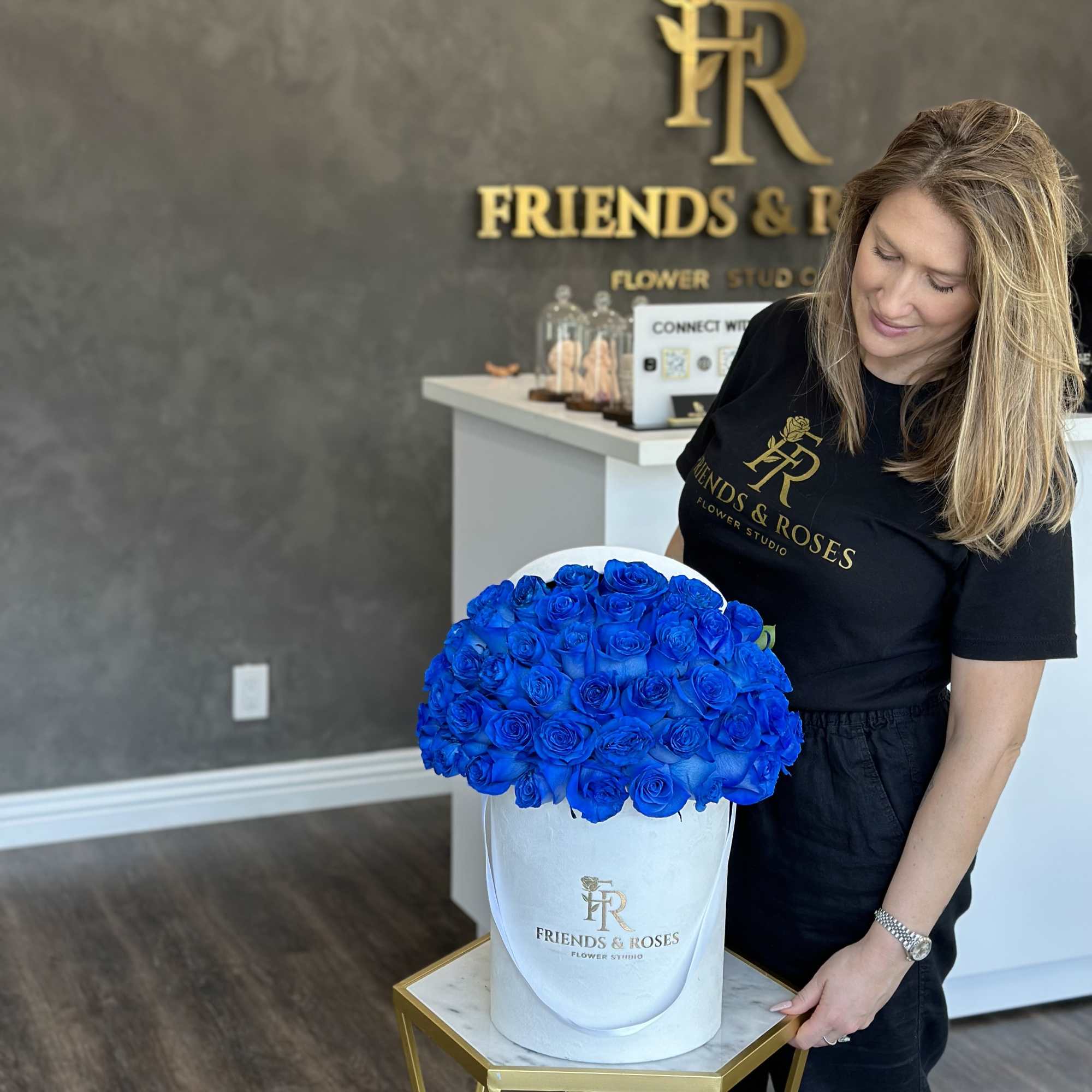 Woman holding a white hatbox filled with bright blue roses