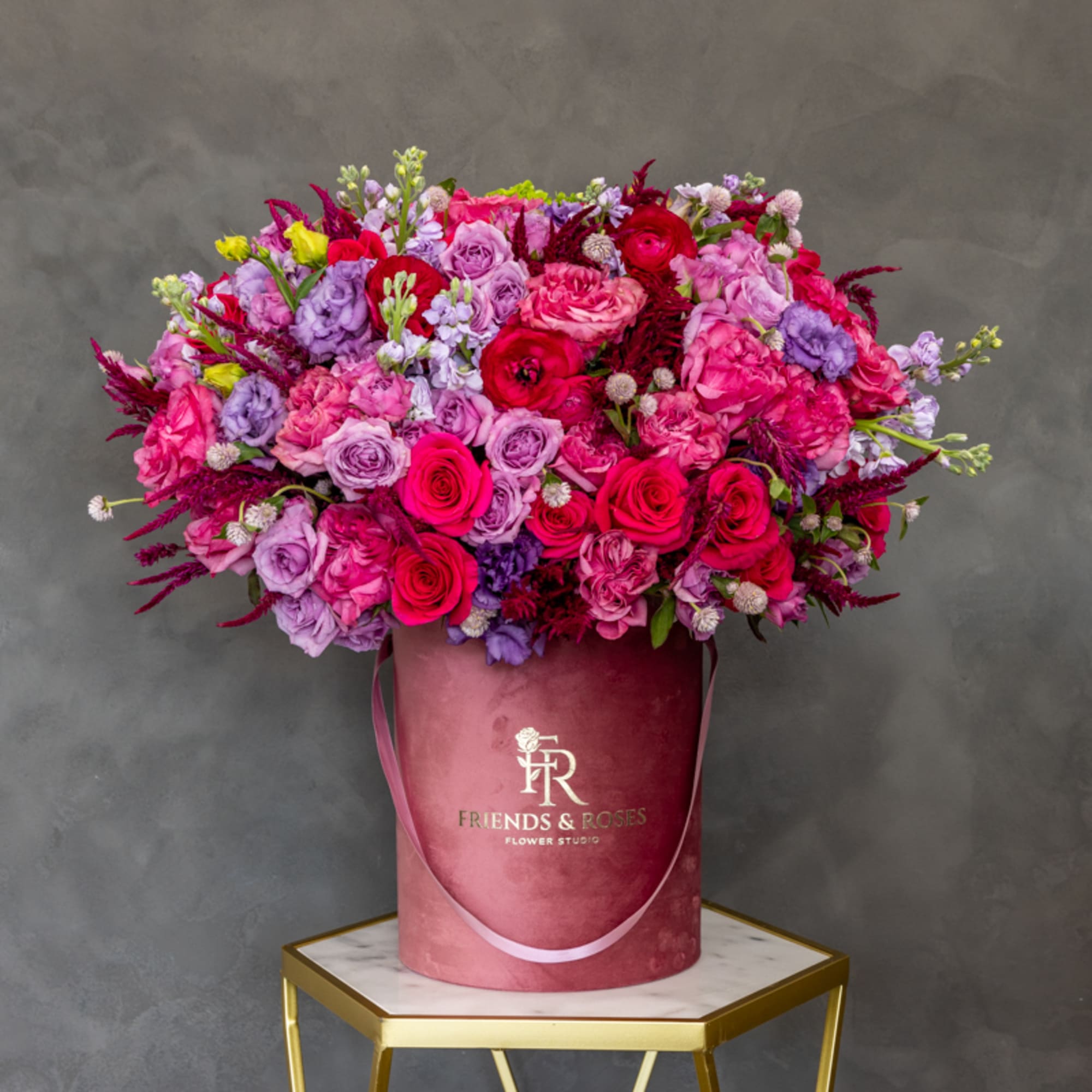 Large bouquet of pink, red, and lavender roses in a pink hatbox