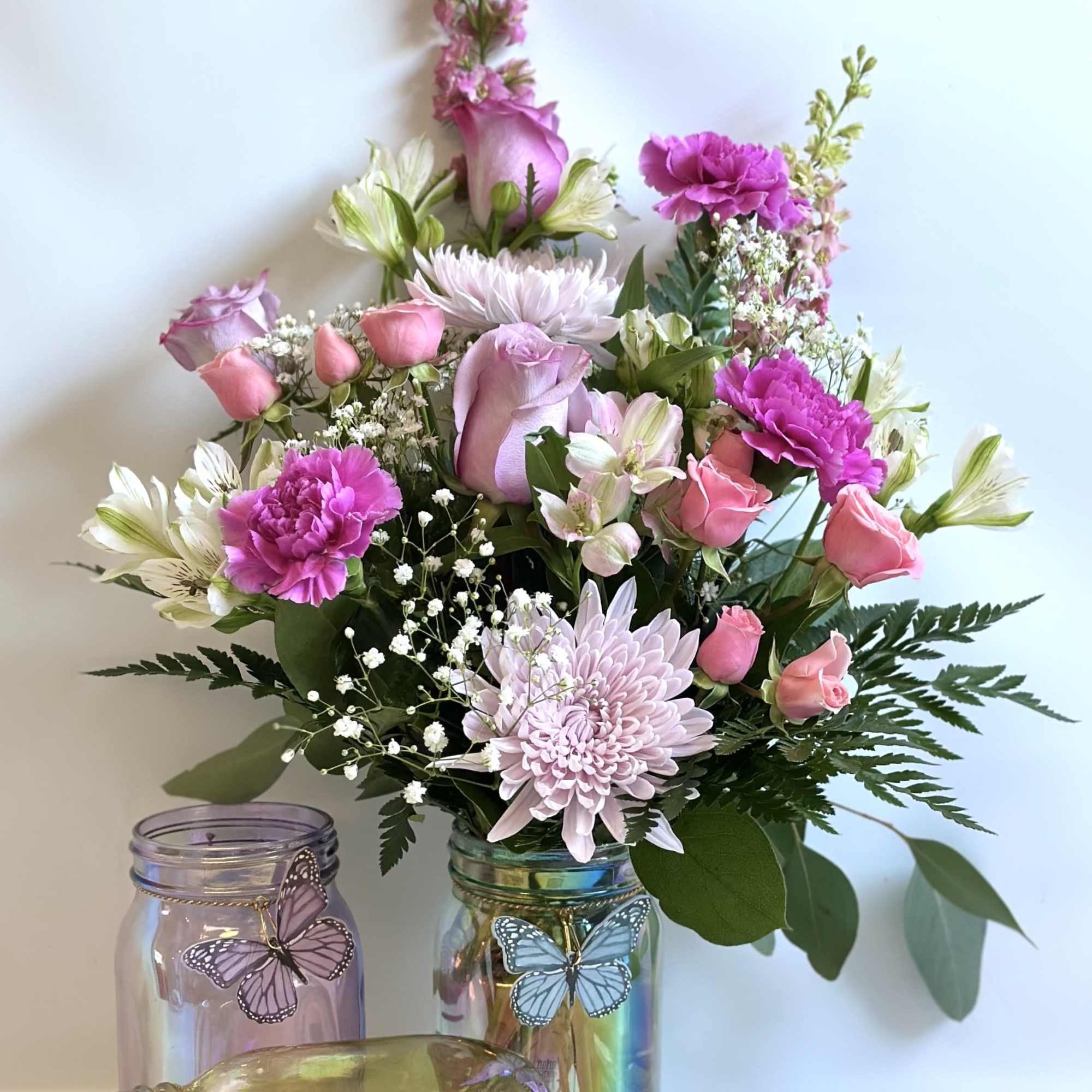 A beautiful iridescent jar with a butterfly charm with pink, lavender and