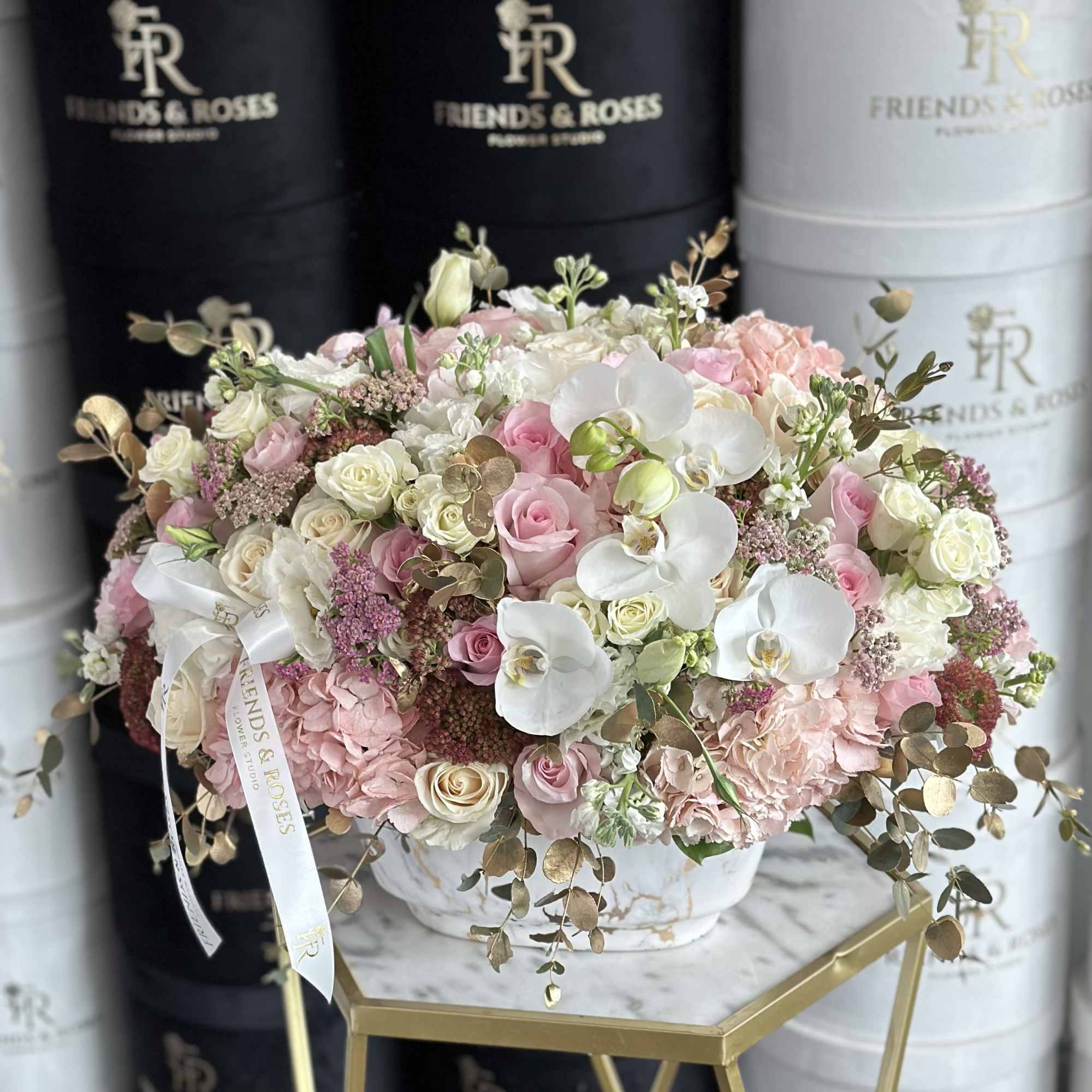 Pink and white floral arrangement in a marble-patterned box with a ribbon