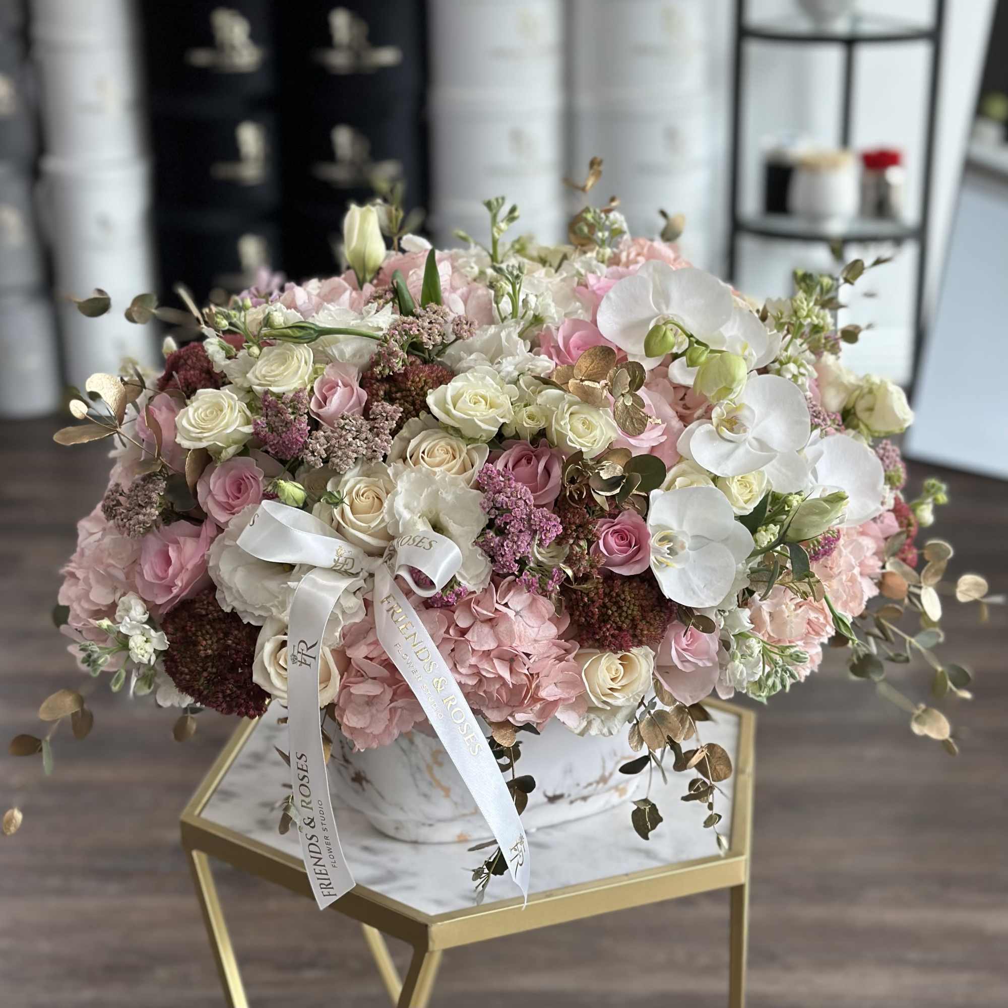 Large pink and white floral arrangement in a marble vase