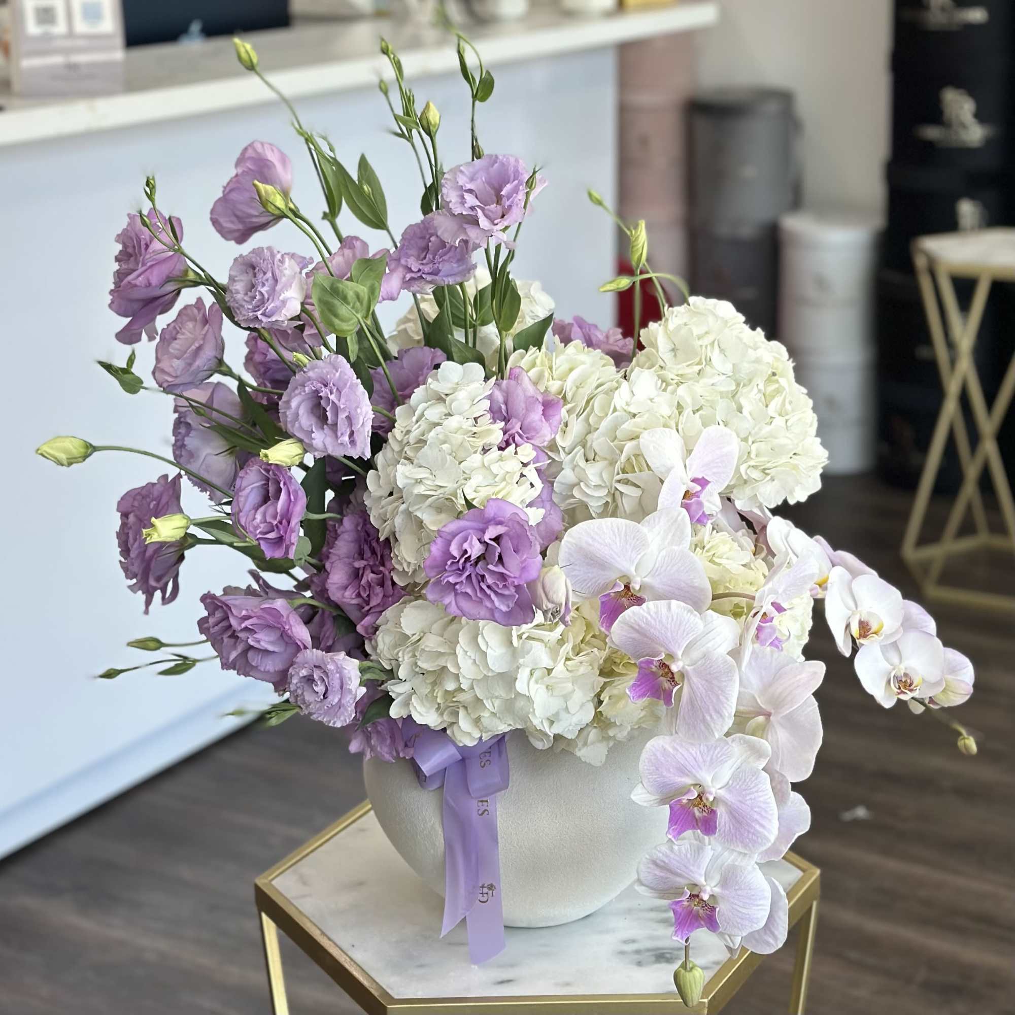 Lavender lisianthus and white hydrangeas in a round vase with white orchids