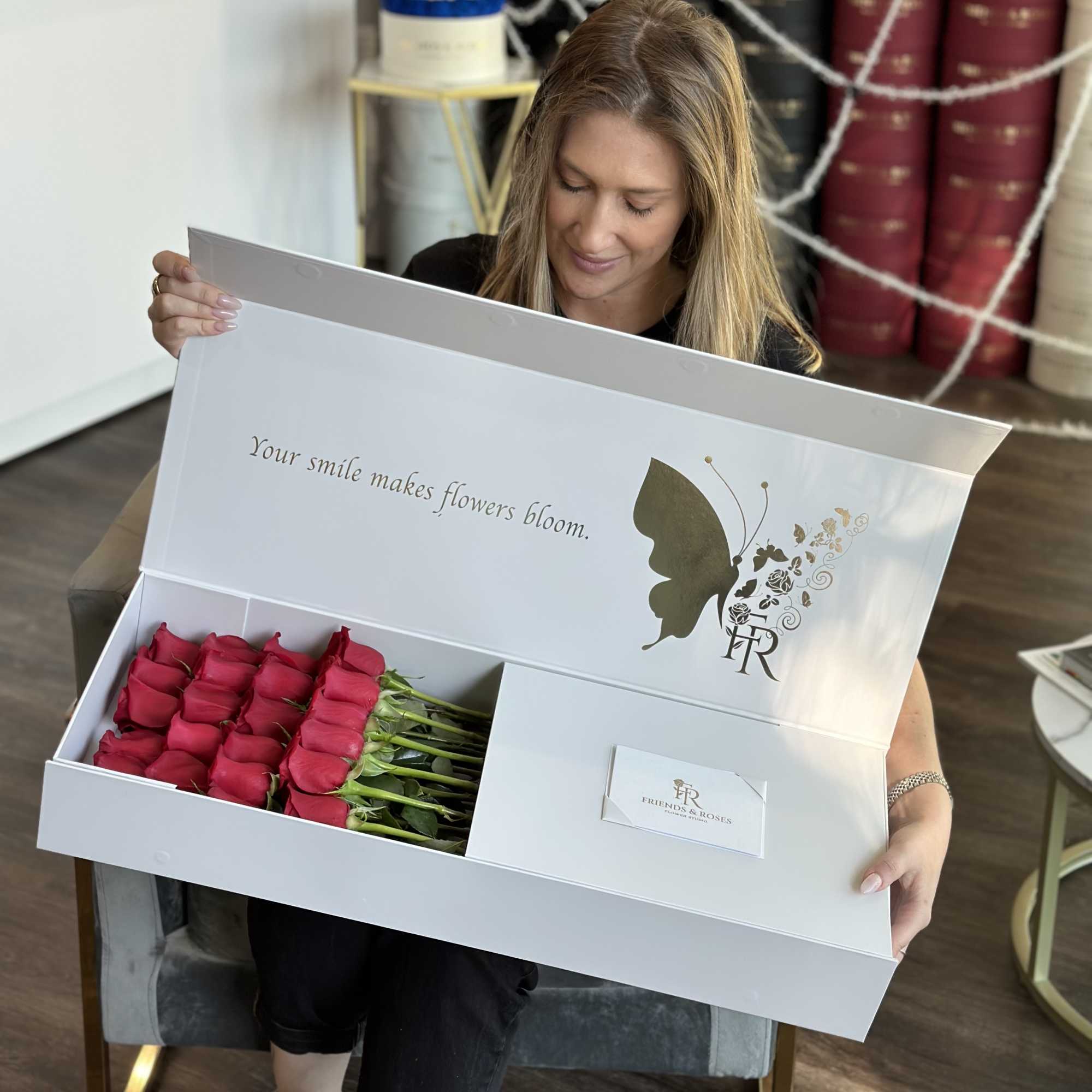 Woman holding an open gift box of red roses