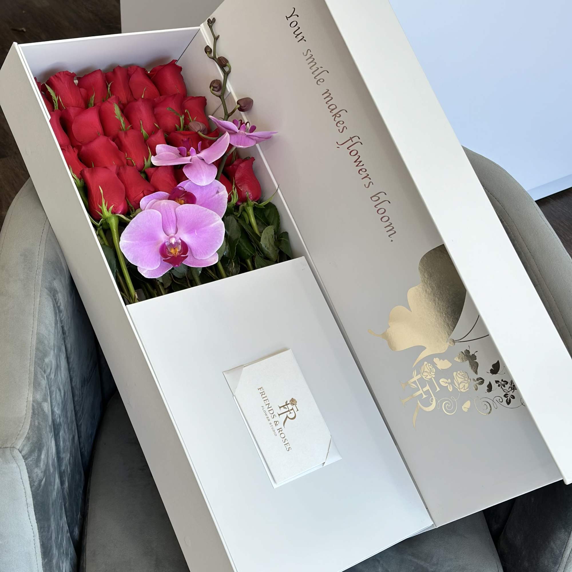 Box of red roses with pink orchids and a card