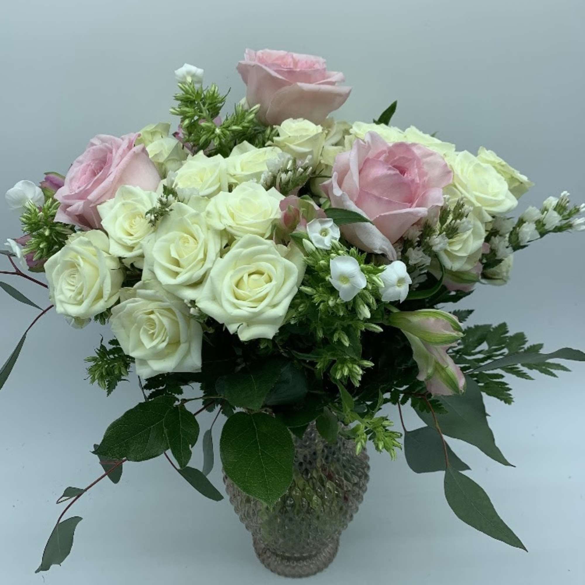 Pink and white roses arranged in a glass vase