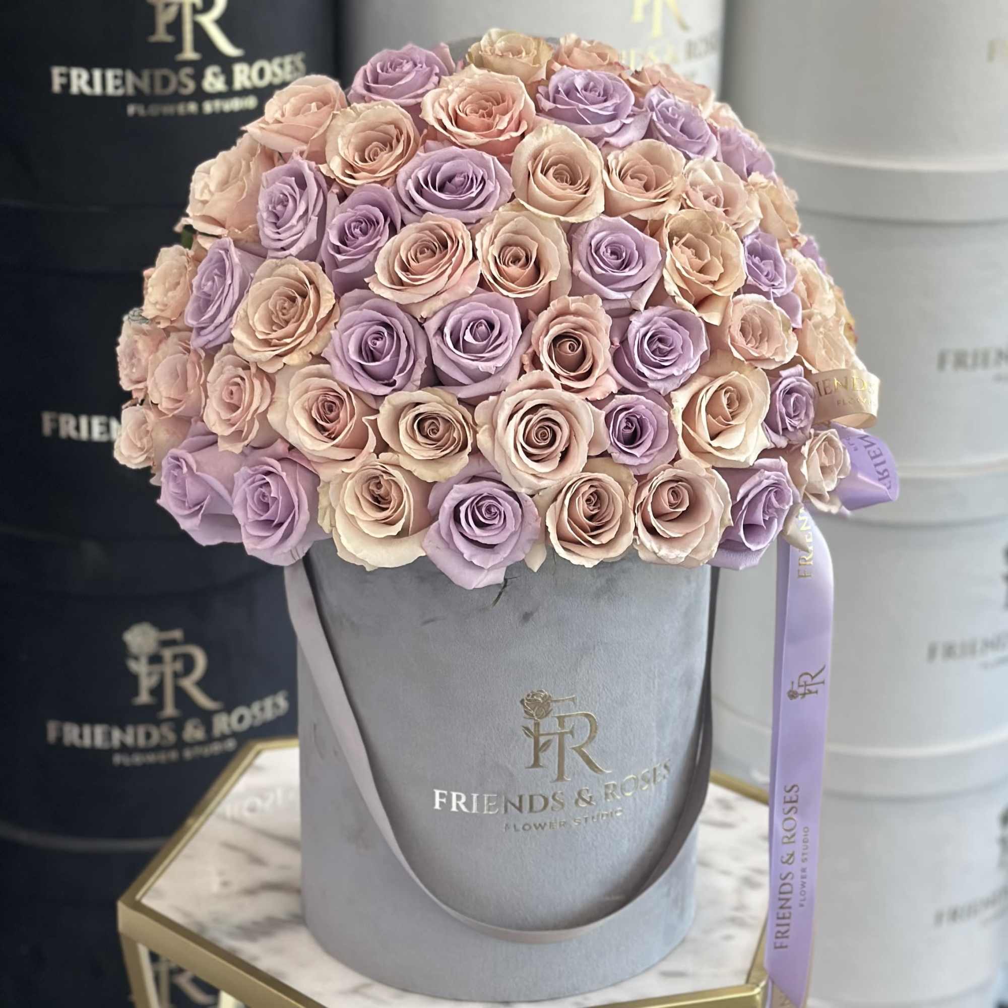 Bouquet of pastel pink and lavender roses in a gray hat box