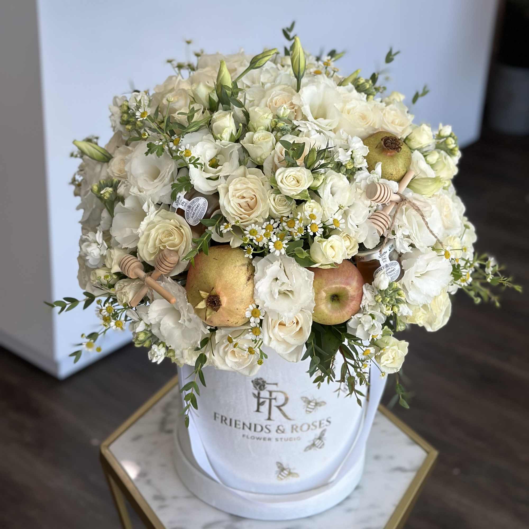 White floral arrangement with apples in a white hatbox