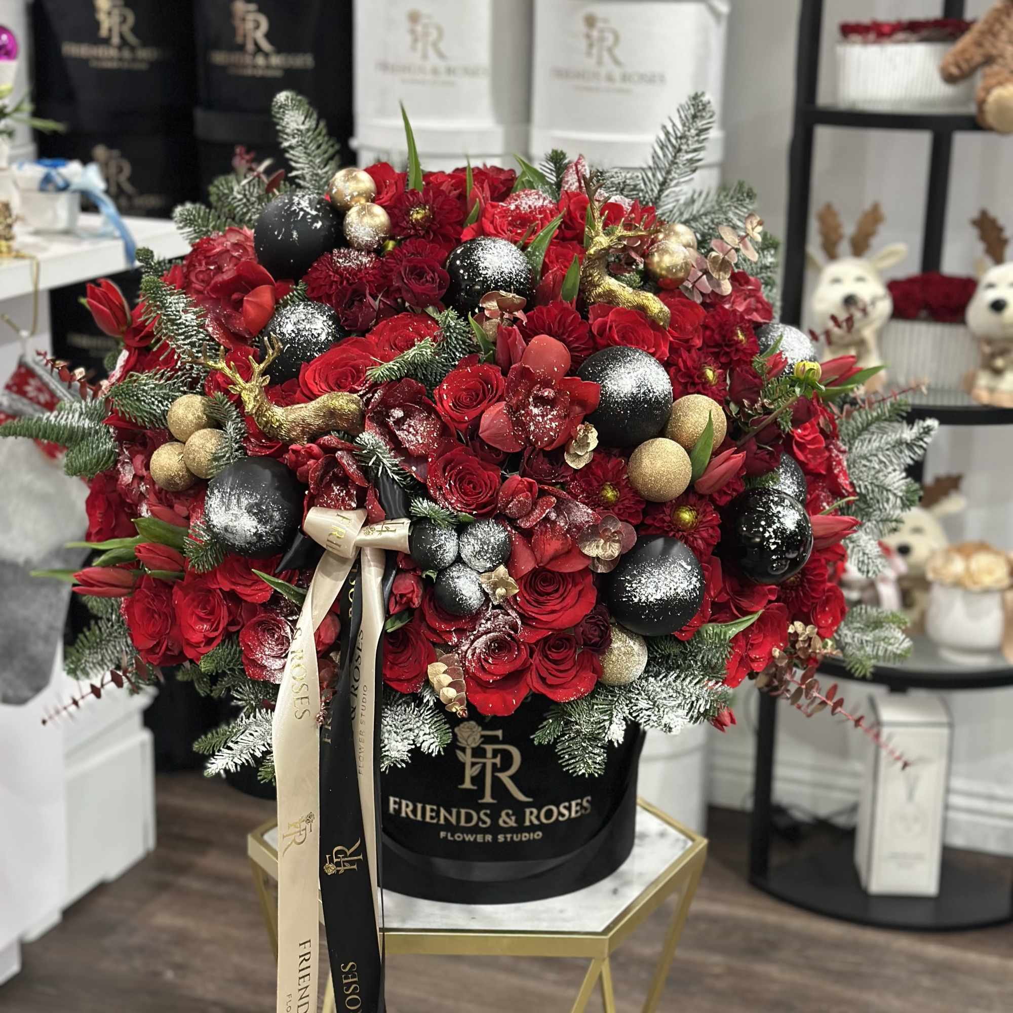 Large red rose arrangement with gold and black ornaments in a black hatbox