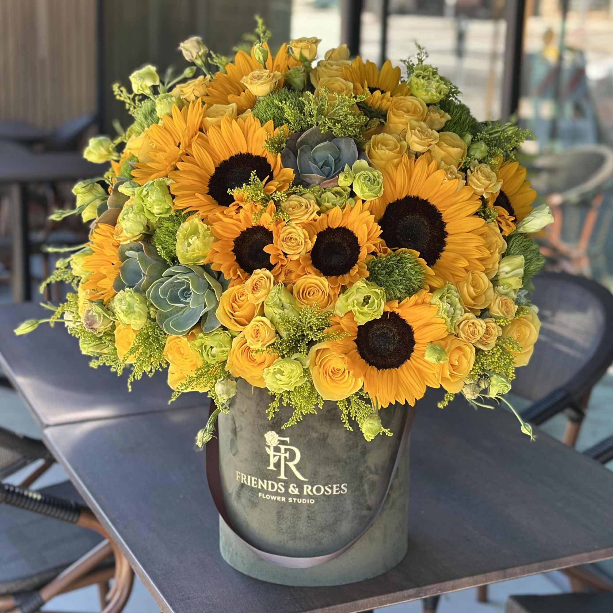 Sunflowers and yellow roses arranged in a gray hatbox