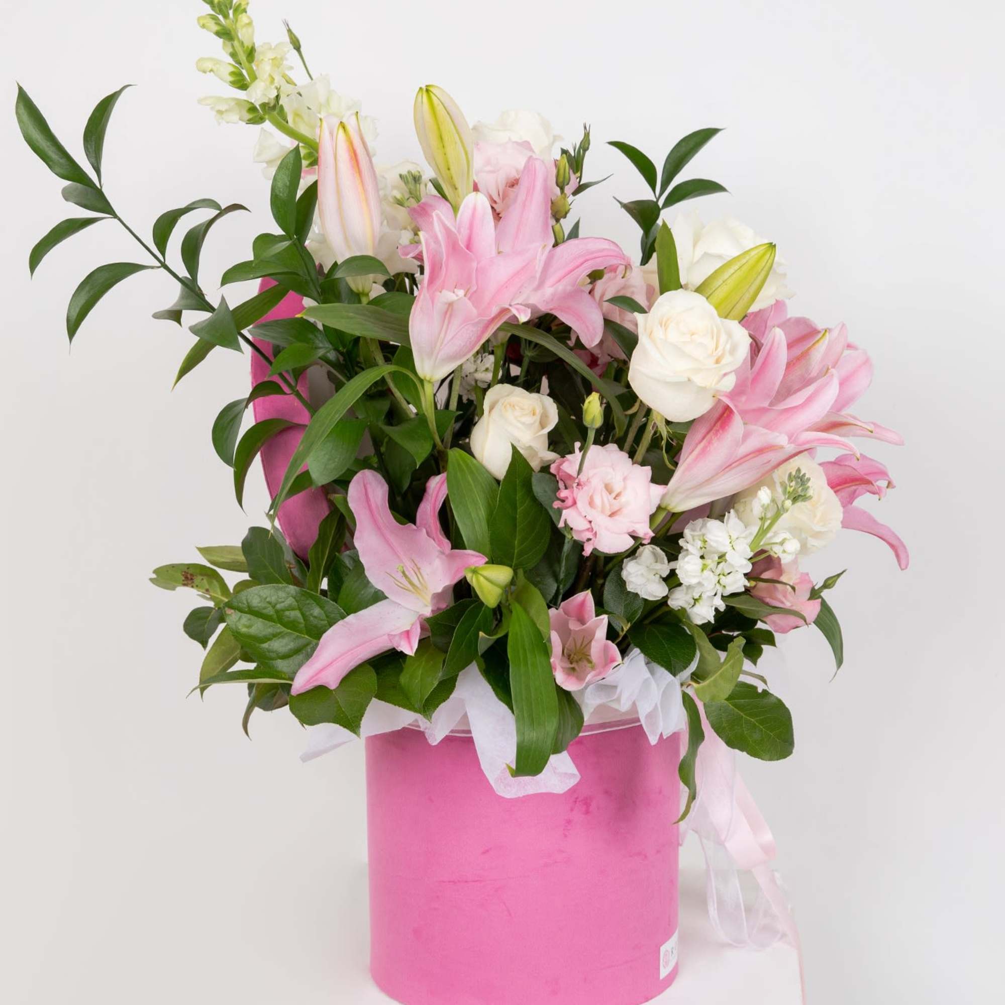 Pink lilies and white roses arranged in a pink box