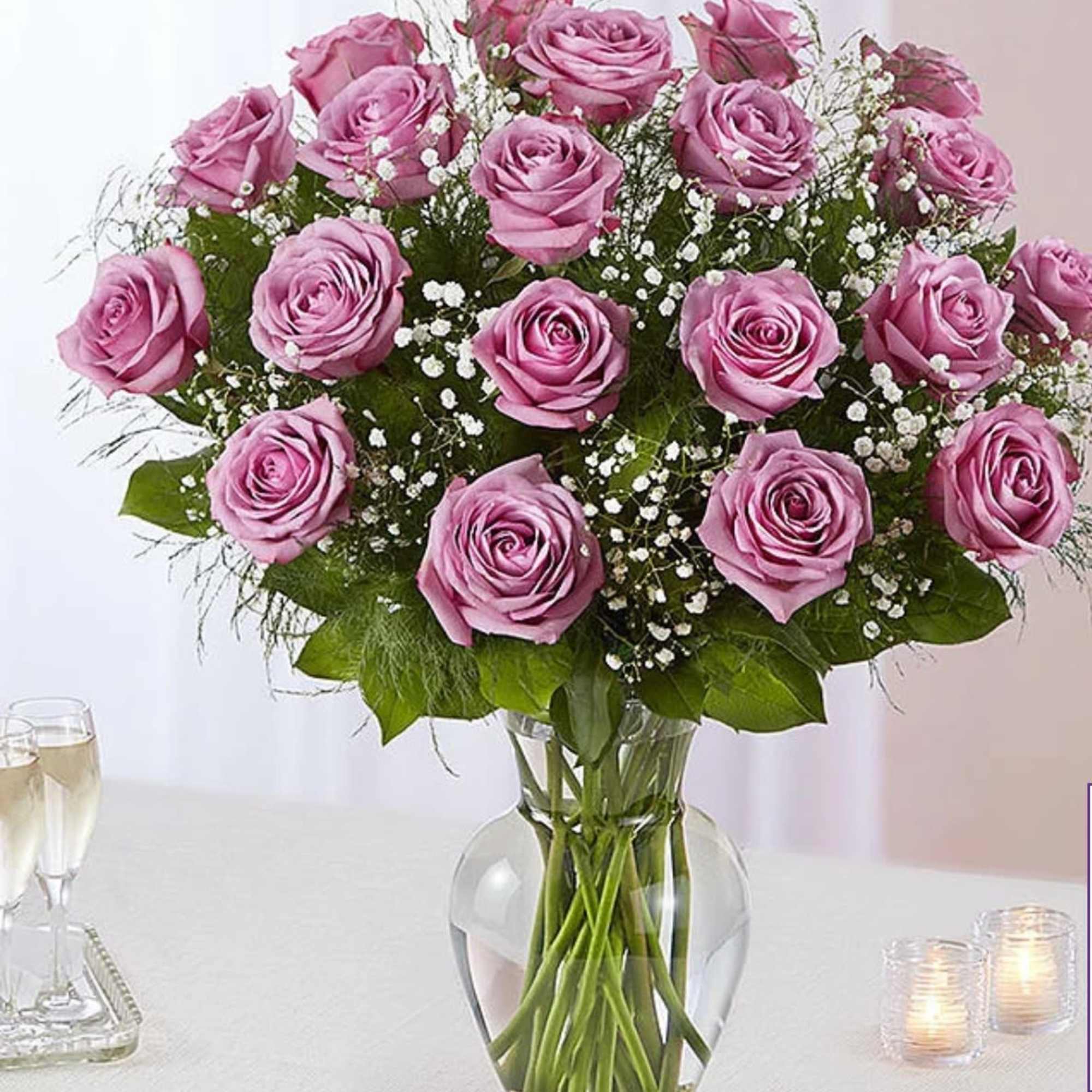 Pink roses arranged in a clear glass vase with baby's breath