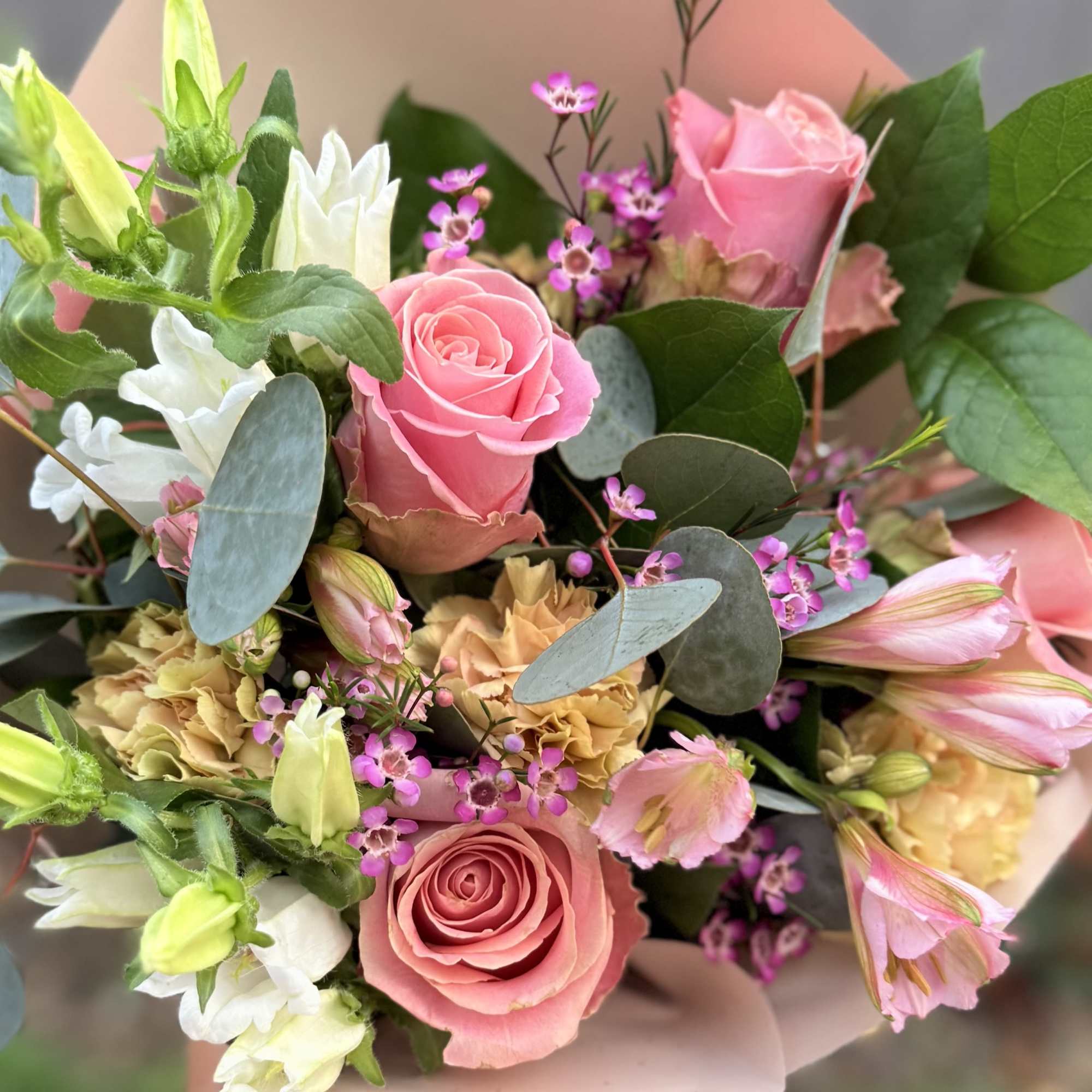 Handheld bouquet of pink roses, white blooms, and small purple flowers