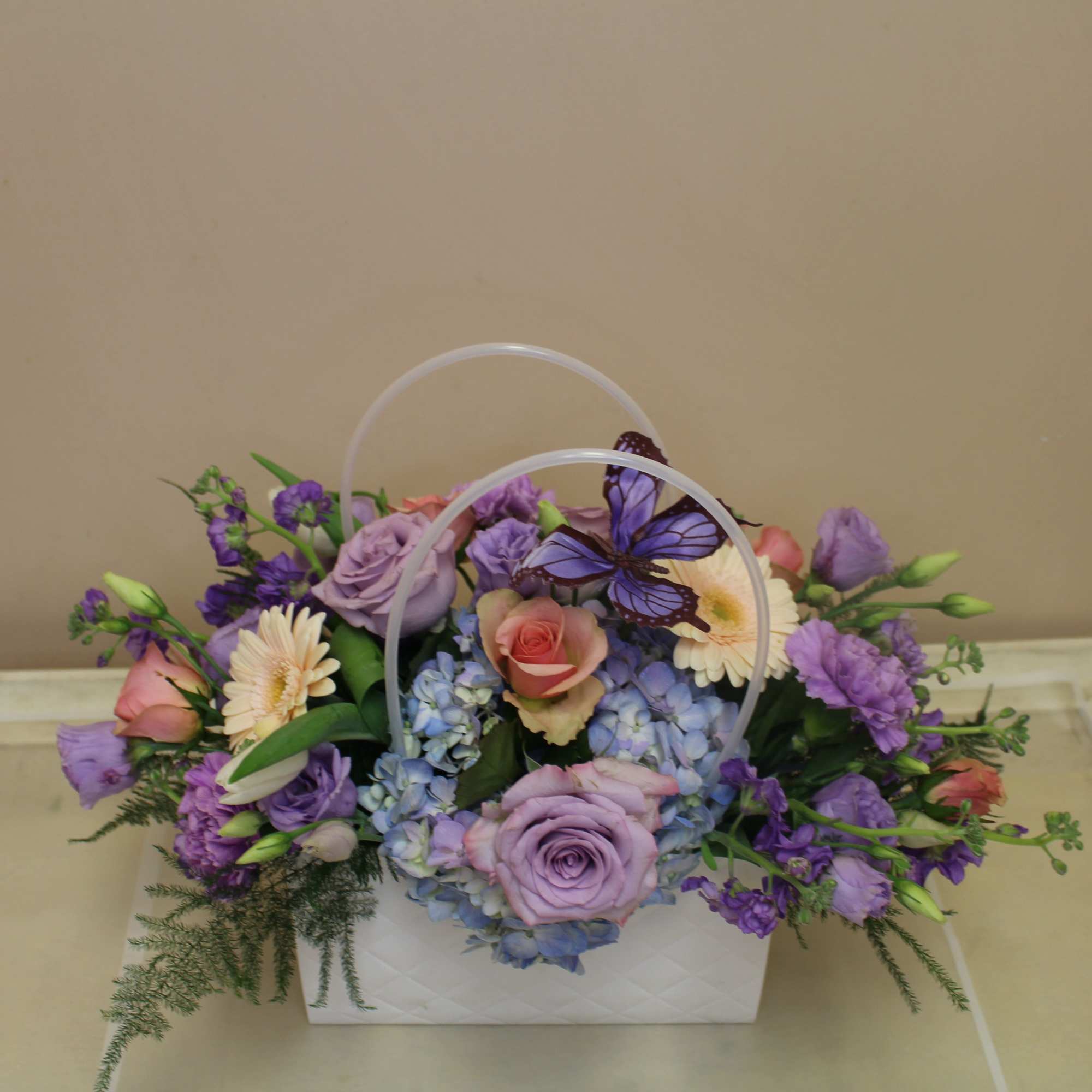 A soft pastel gift arrangement in a decorative white quilted pocketbook, this