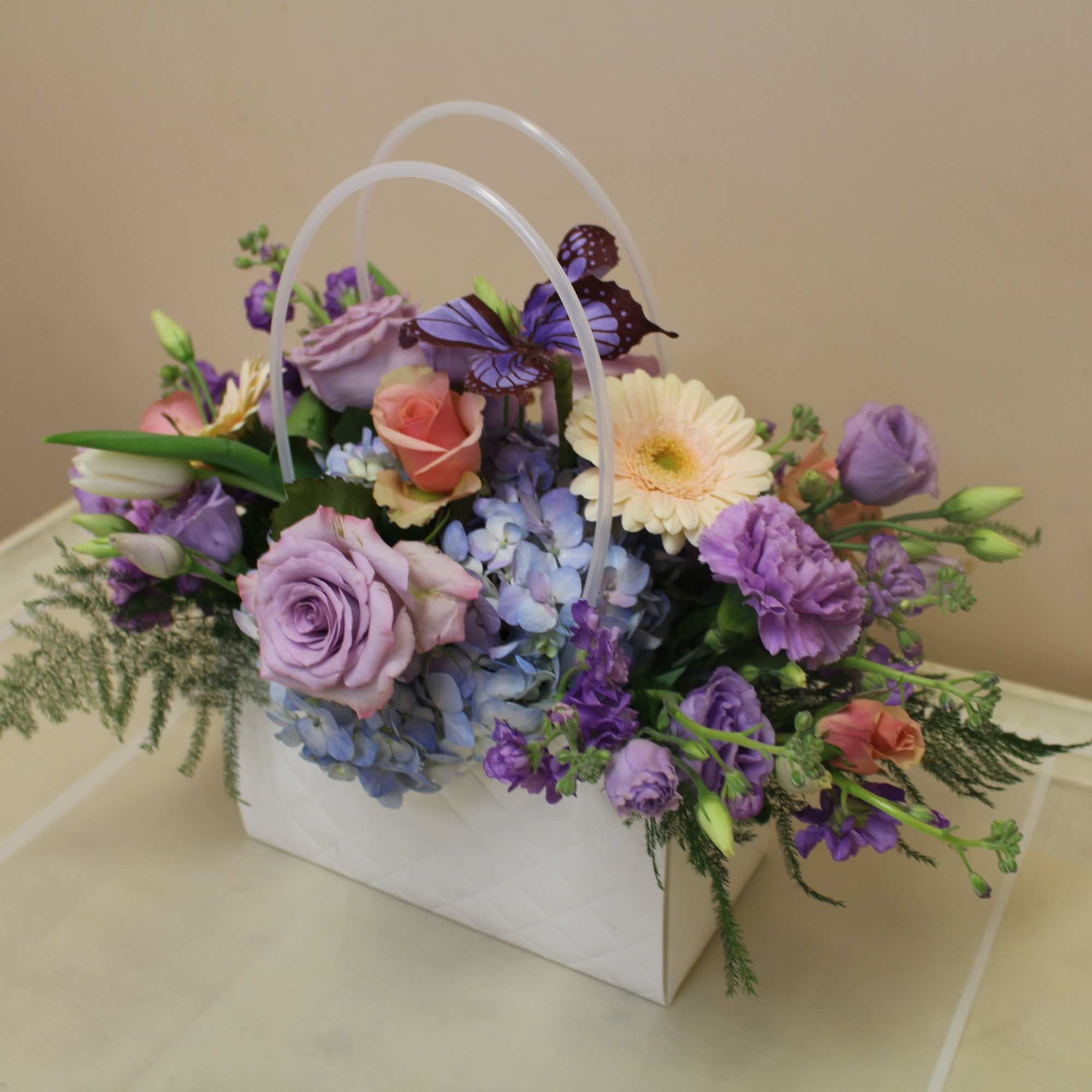 A soft pastel gift arrangement in a decorative white quilted pocketbook, this