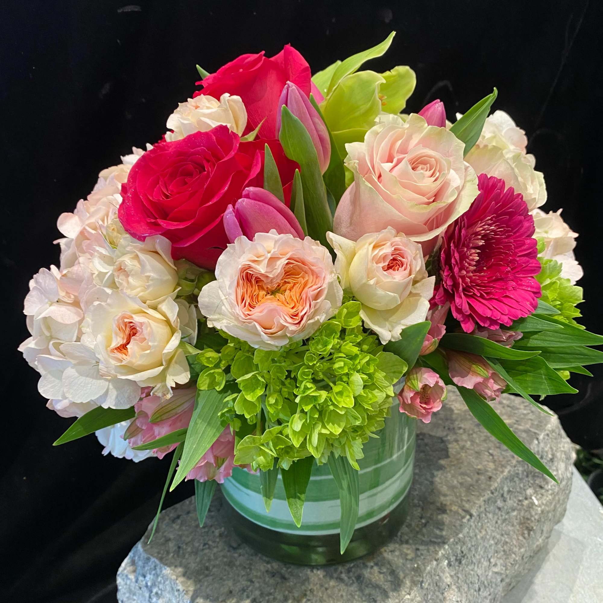 Mixed bouquet of pink and white roses with green hydrangea in a glass vase