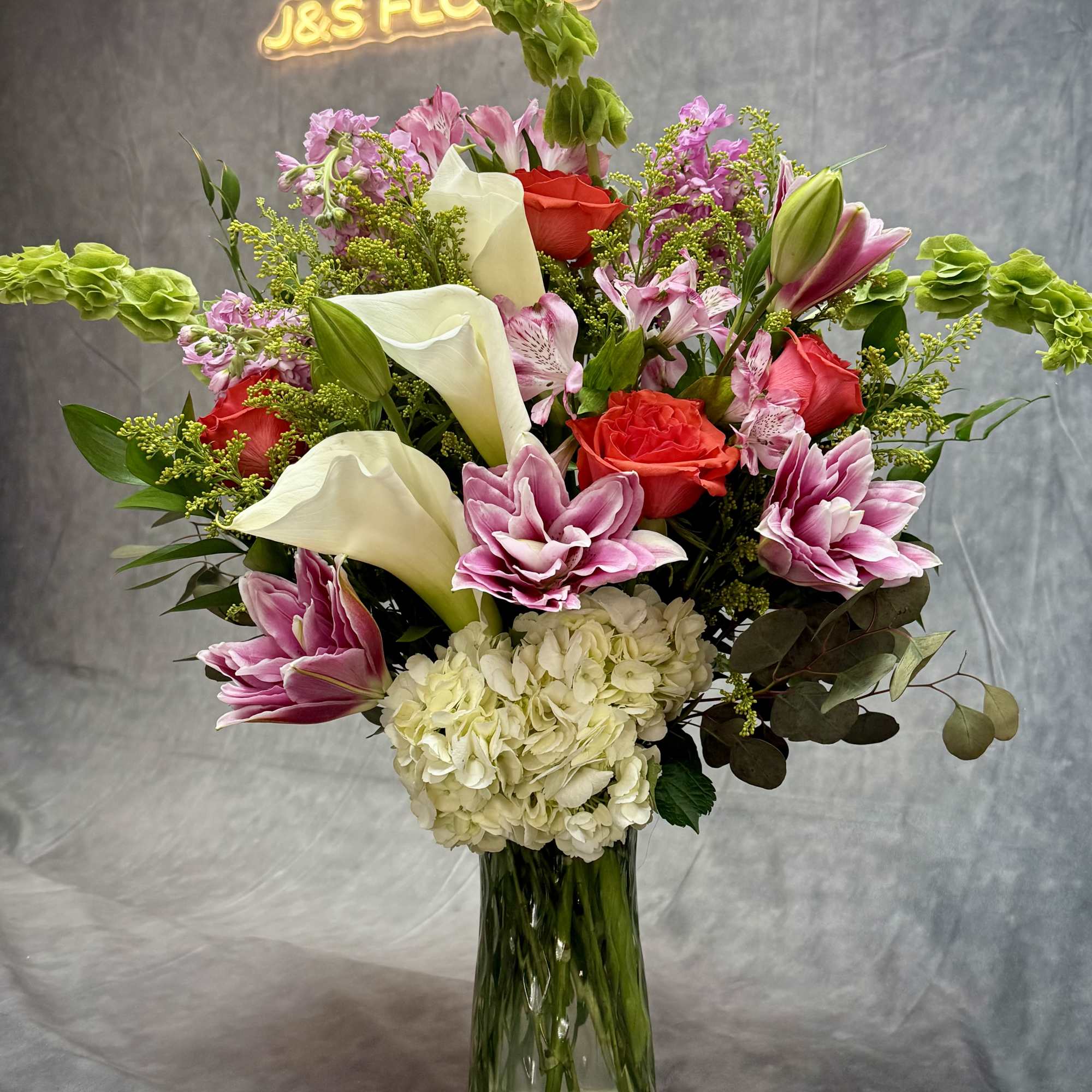 Mixed bouquet with roses, calla lilies, hydrangea, and pink lilies in a glass vase