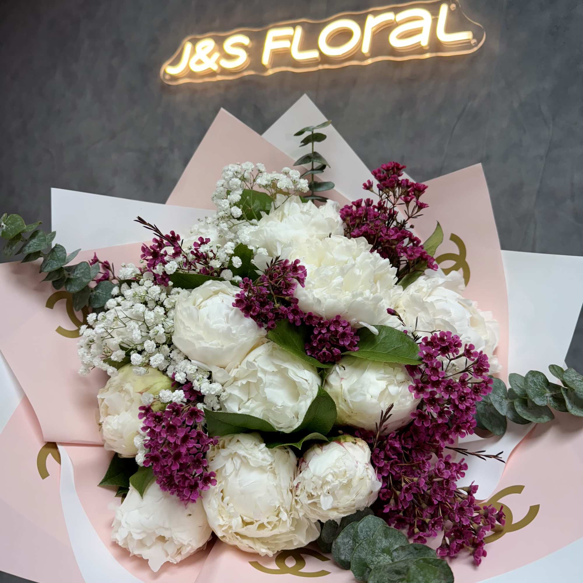 White peony bouquet with magenta filler flowers and pastel wrapping
