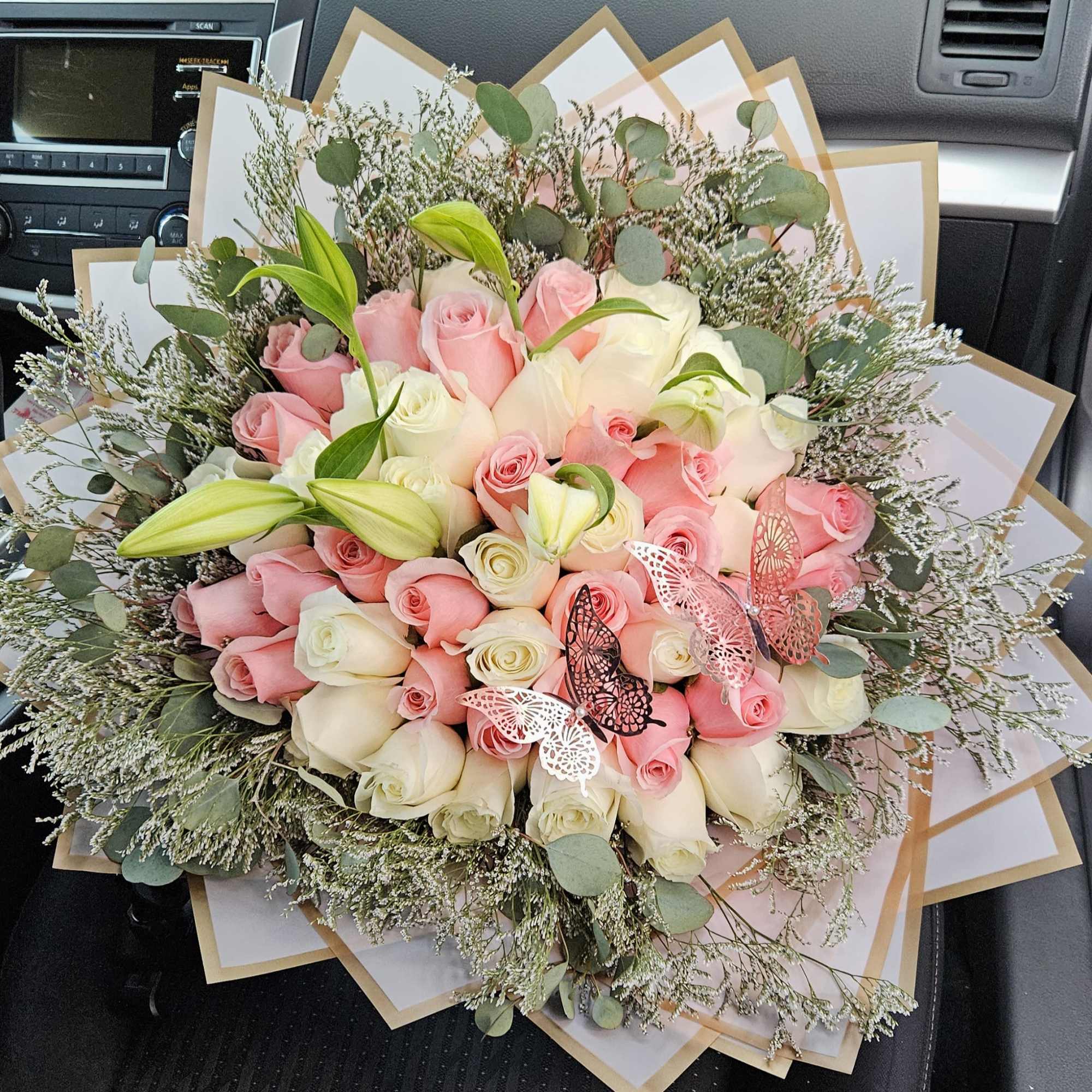 Bouquet of pink and white roses with lilies and butterfly accents