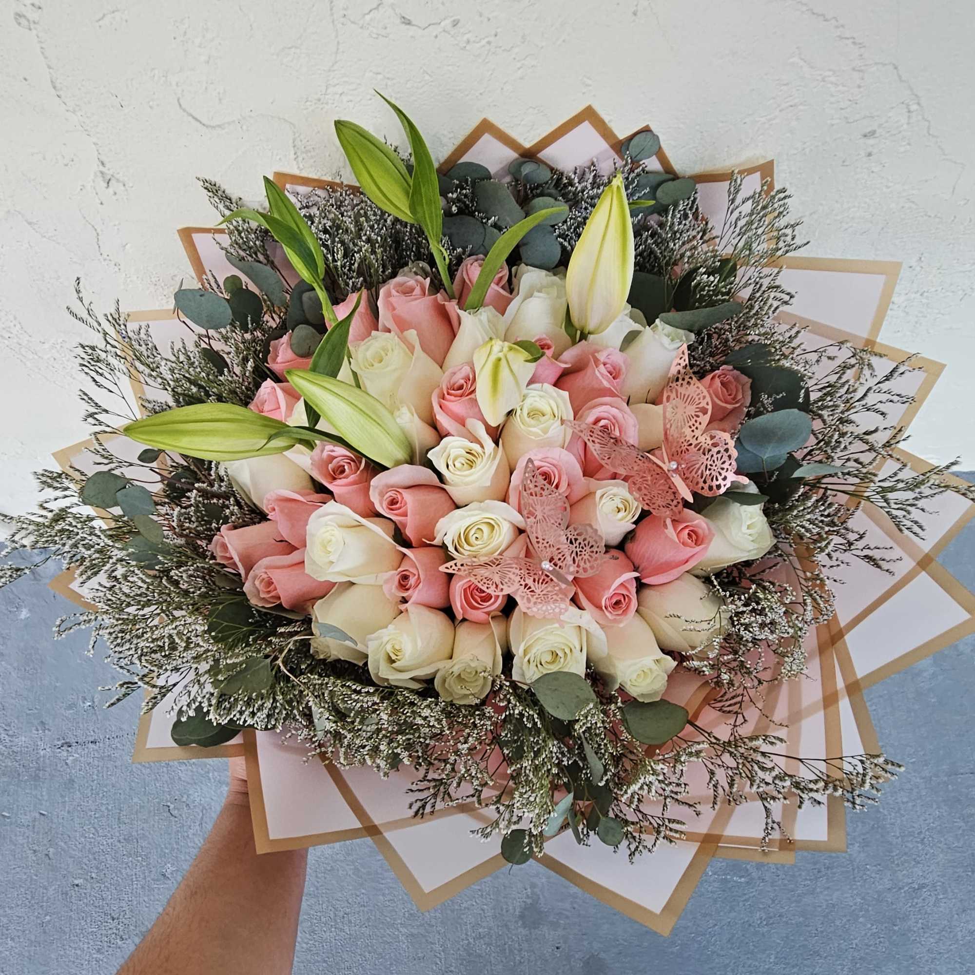 Bouquet of pink and white roses with lily buds and pink butterfly decorations