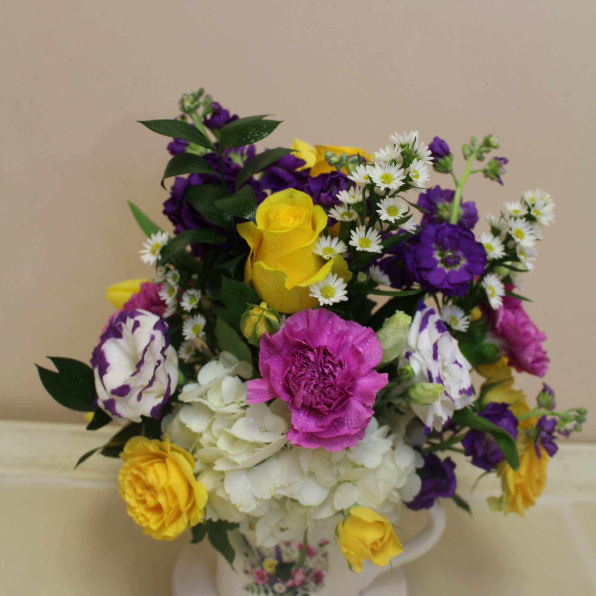A bright, playful floral arrangement presented in a ceramic mug and saucer