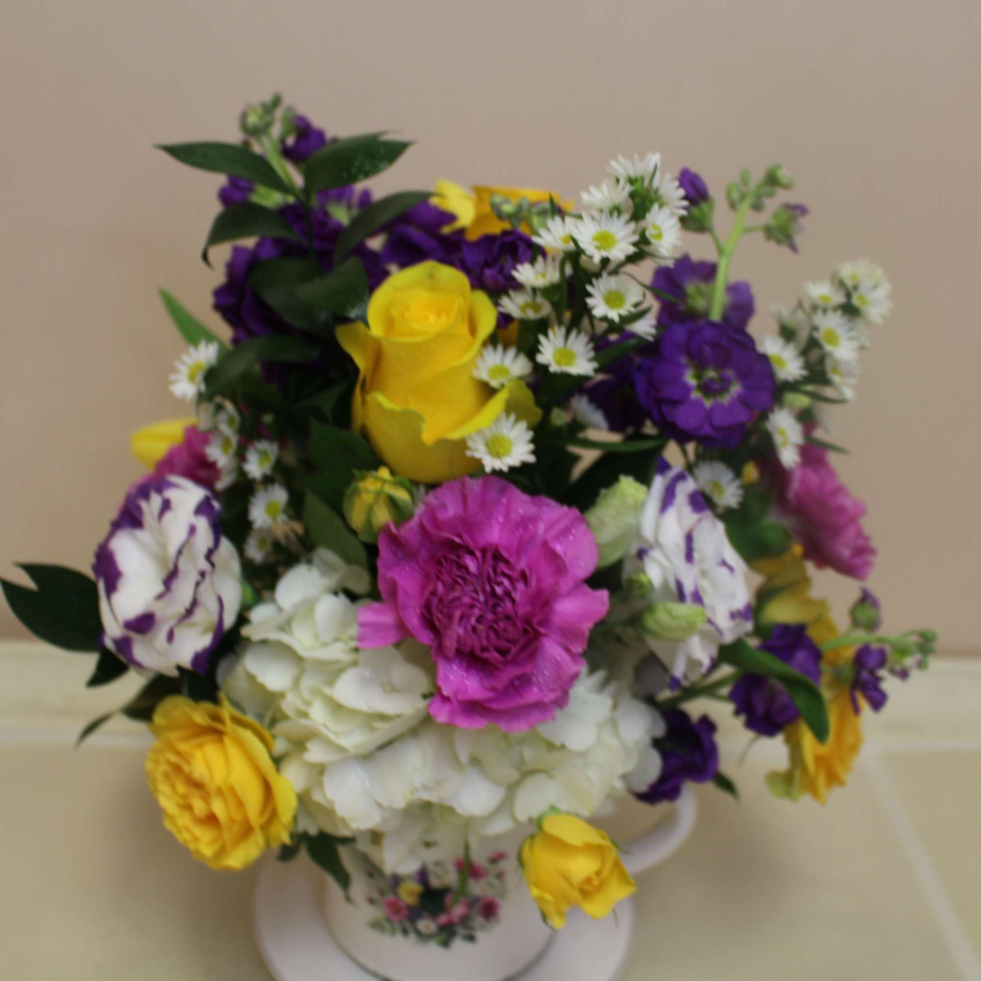 A bright, playful floral arrangement presented in a ceramic mug and saucer