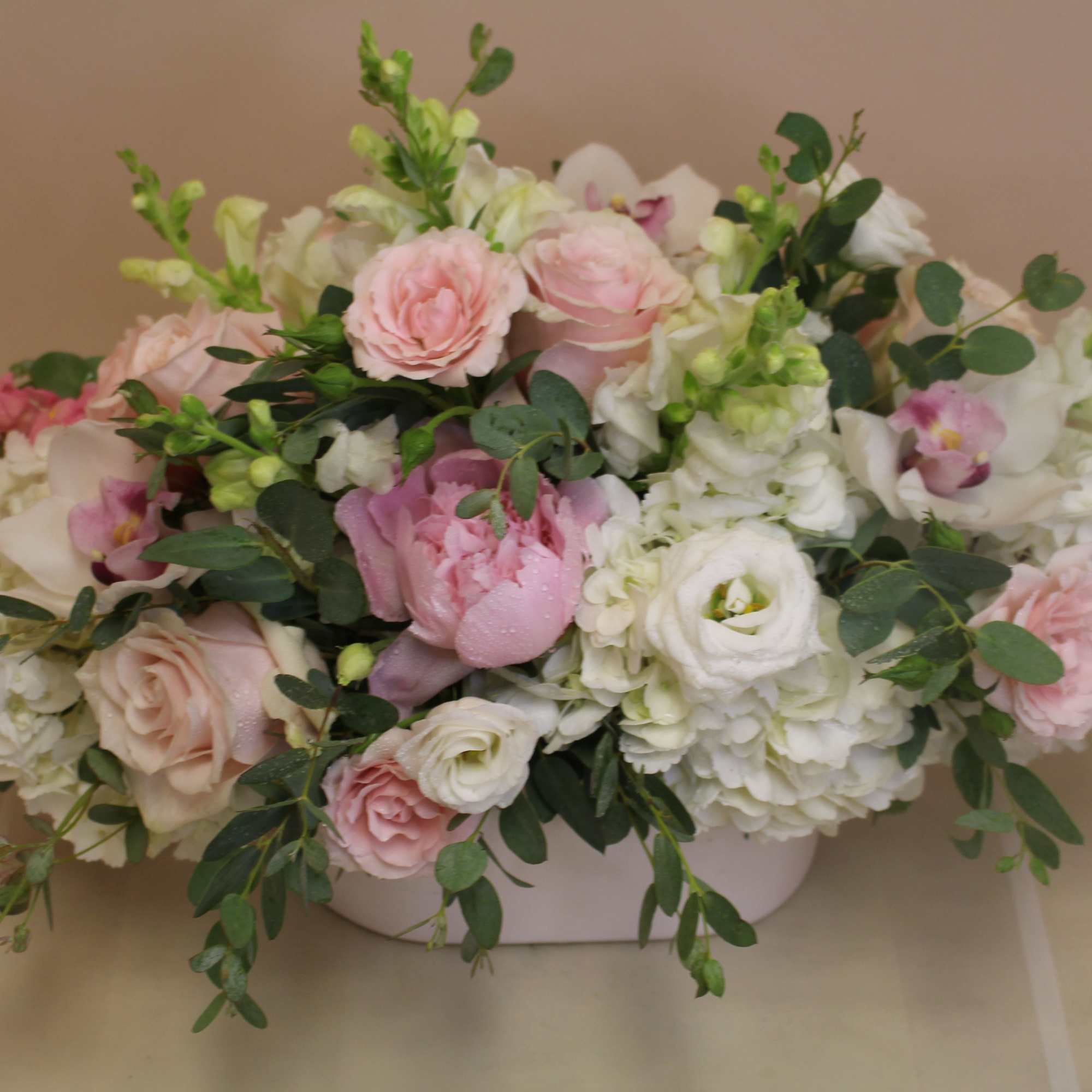 Soft blush roses and ruffled peonies nestle among creamy white hydrangeas and