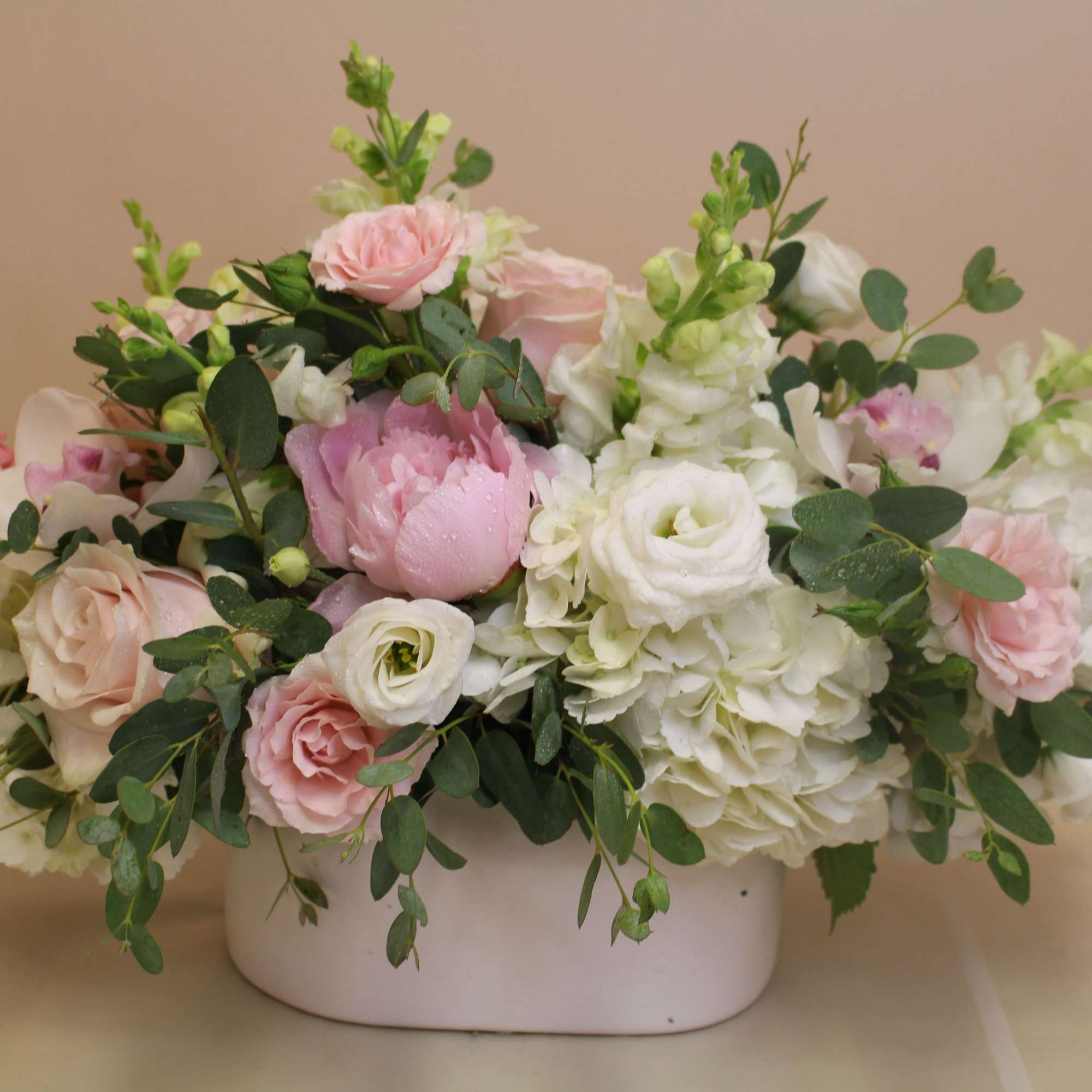 Soft blush roses and ruffled peonies nestle among creamy white hydrangeas and