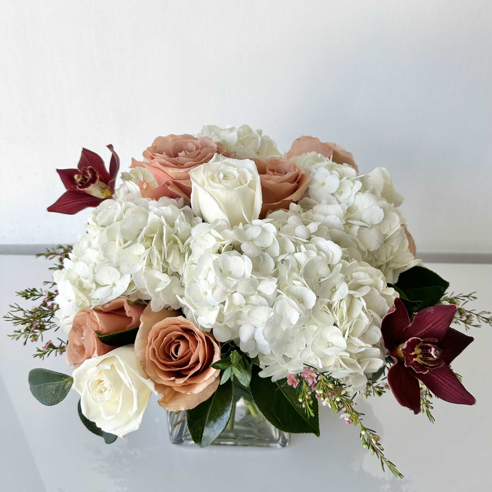 An elegant arrangement of hydrangeas, roses, and cymbidium orchids in a 5"