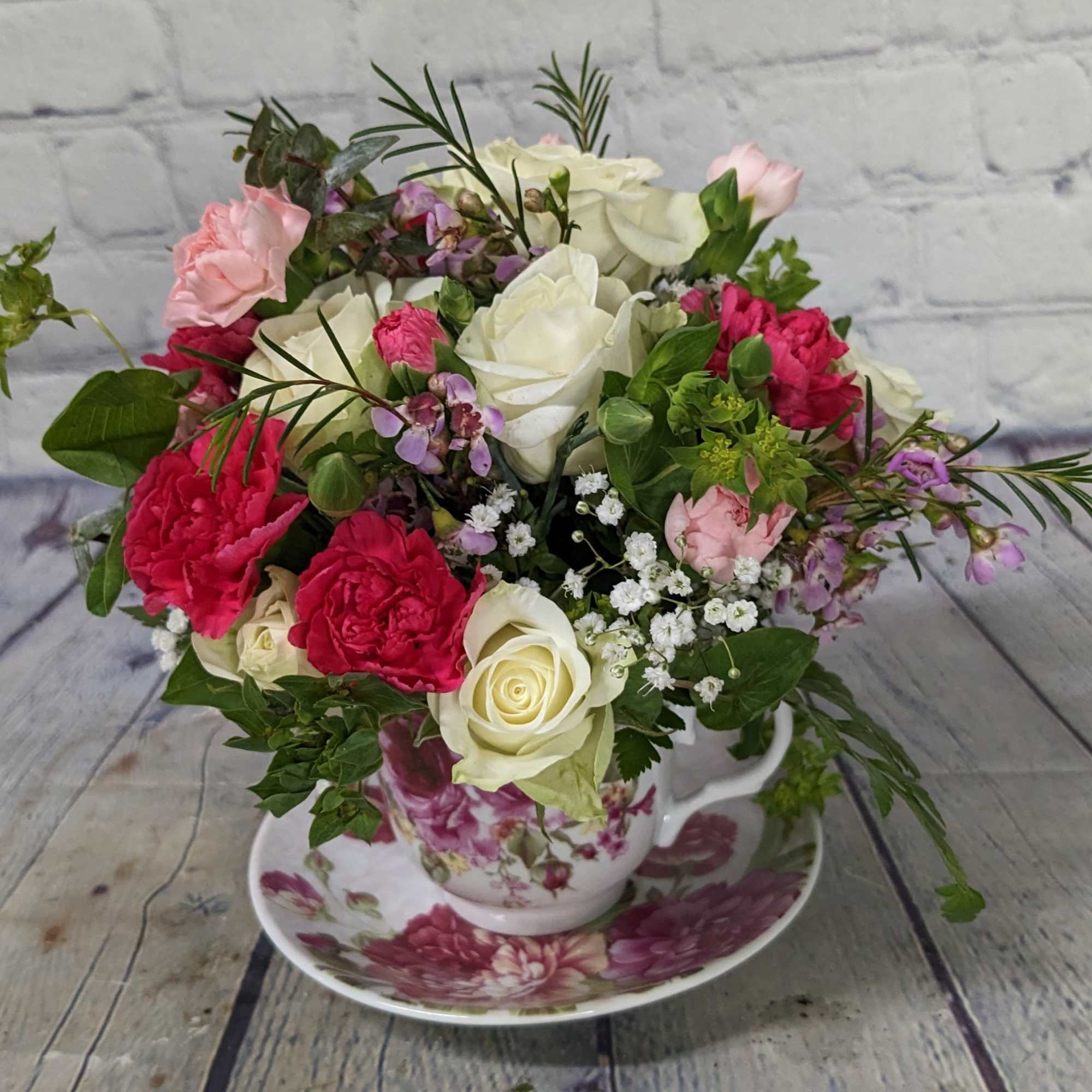 Bouquet of pink and white roses in a floral teacup and saucer