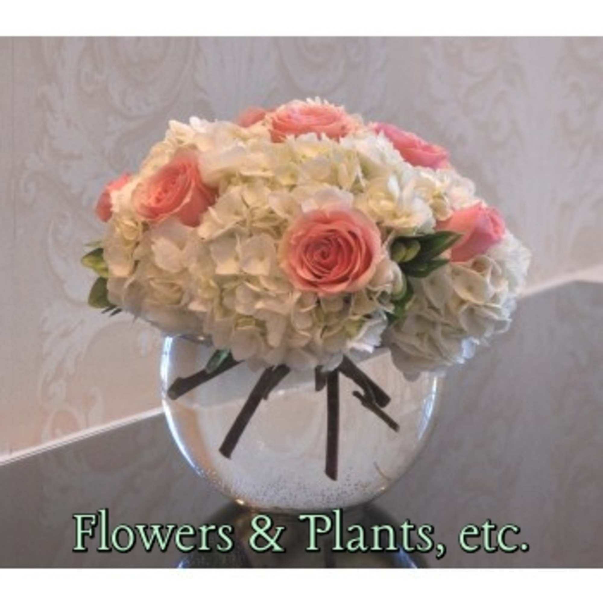 Pink roses and white hydrangeas in a clear glass vase with a black ribbon