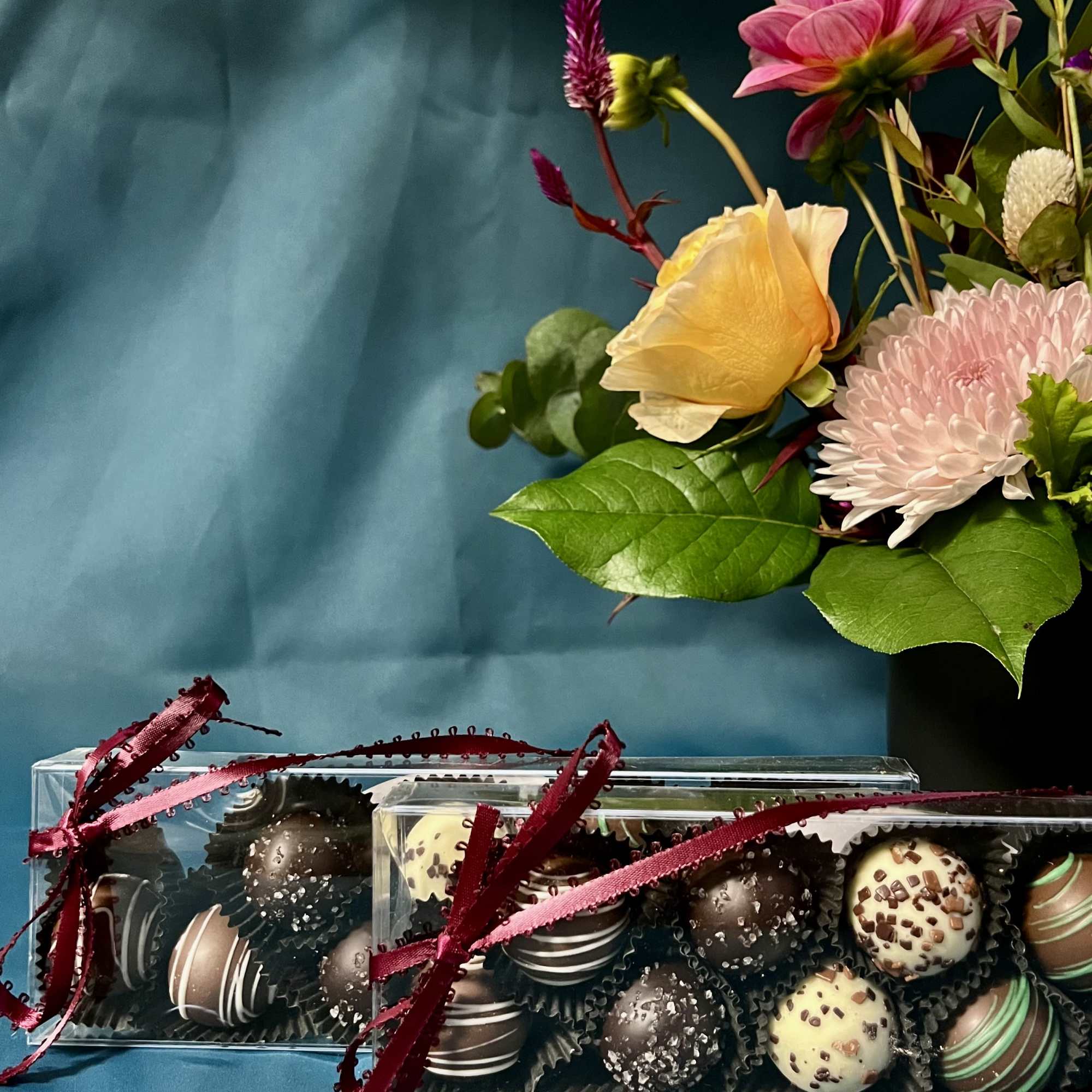Gift set with mixed flower arrangement in a black vase and two boxes of assorted chocolate truffles