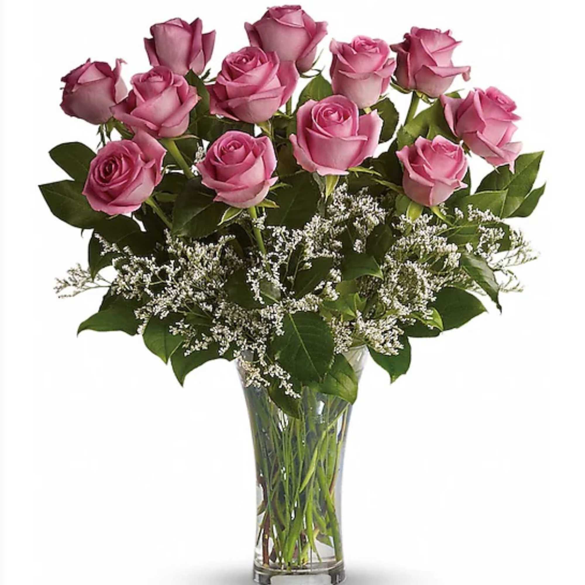 Tall clear vase of pink roses with white filler flowers