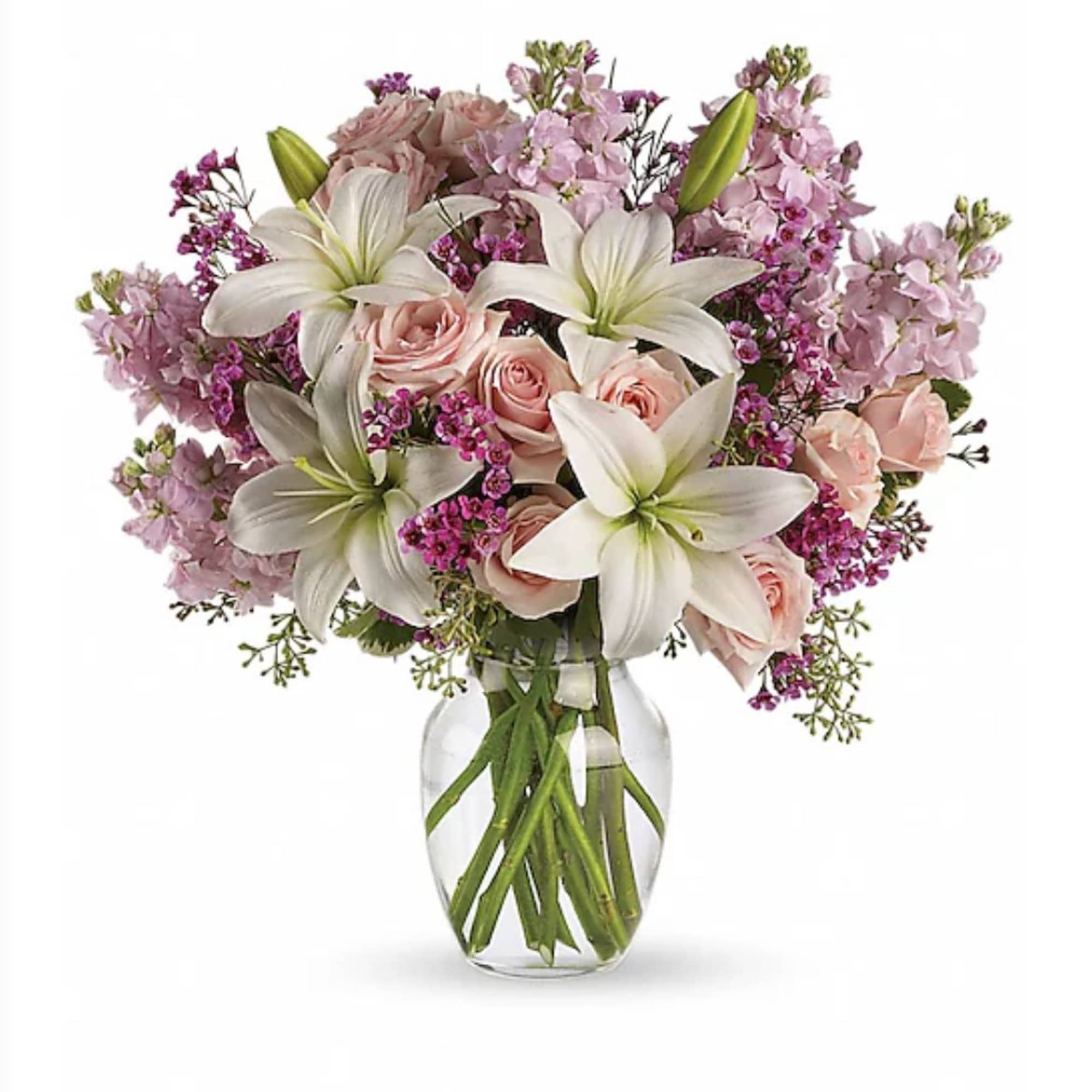 Bouquet of white lilies and light pink roses with purple accents in a clear glass vase