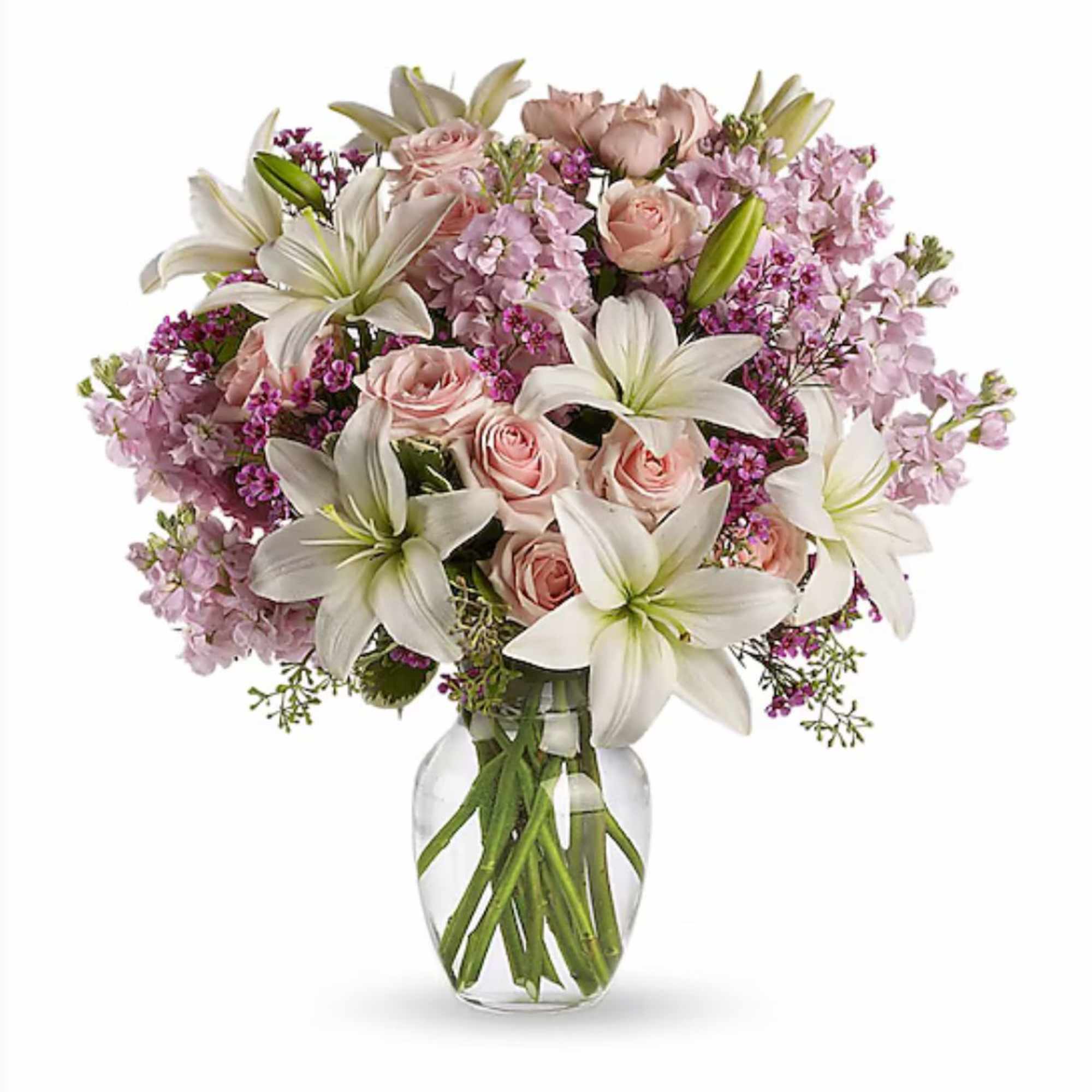 Arrangement of white lilies and pale pink roses with lavender blooms in a clear glass vase