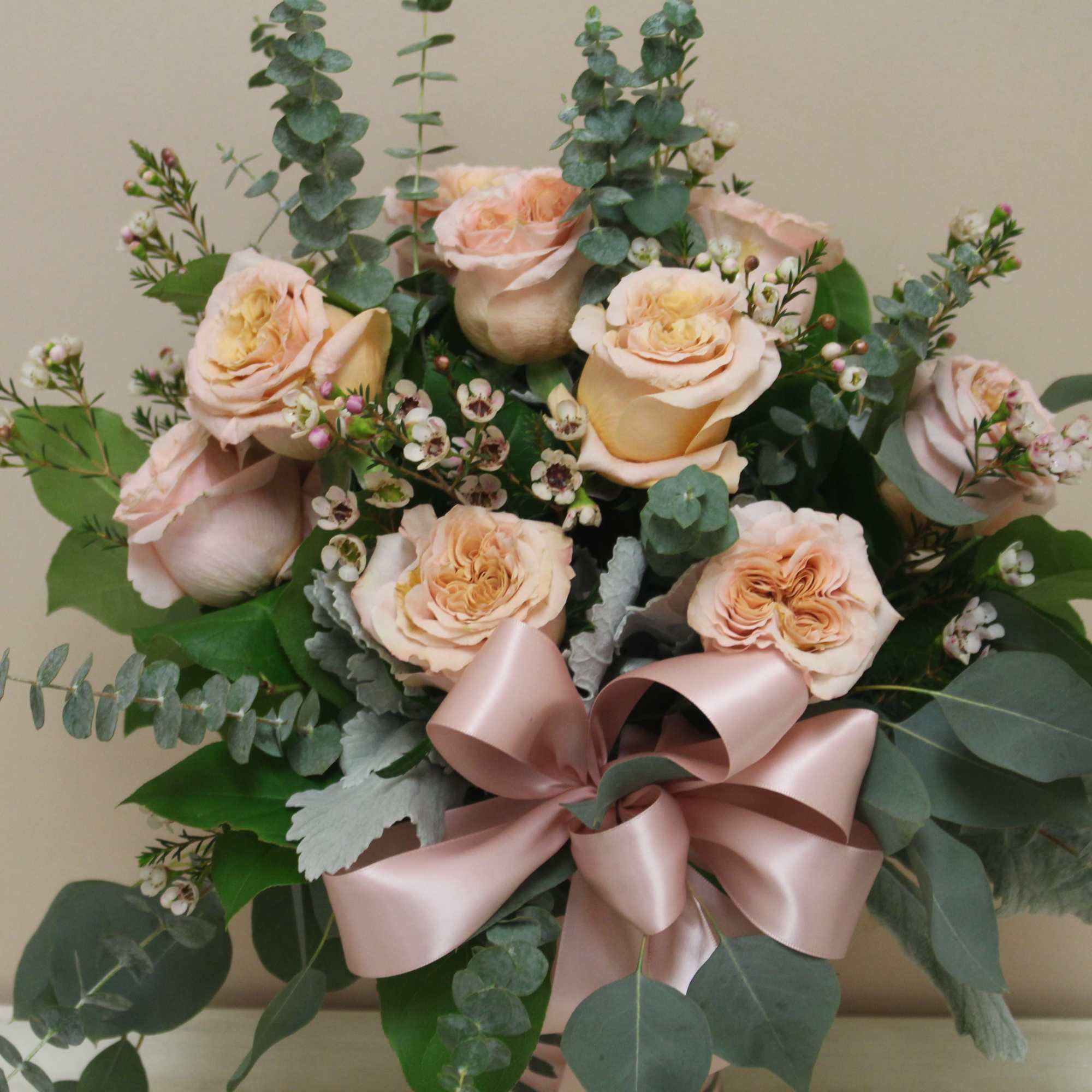 Peach roses with eucalyptus and a pink ribbon bow