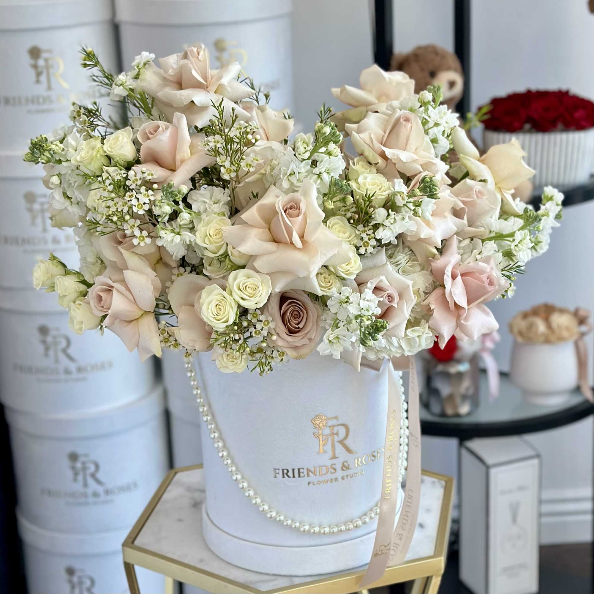 Blush and white roses arranged in a white hatbox with a ribbon.