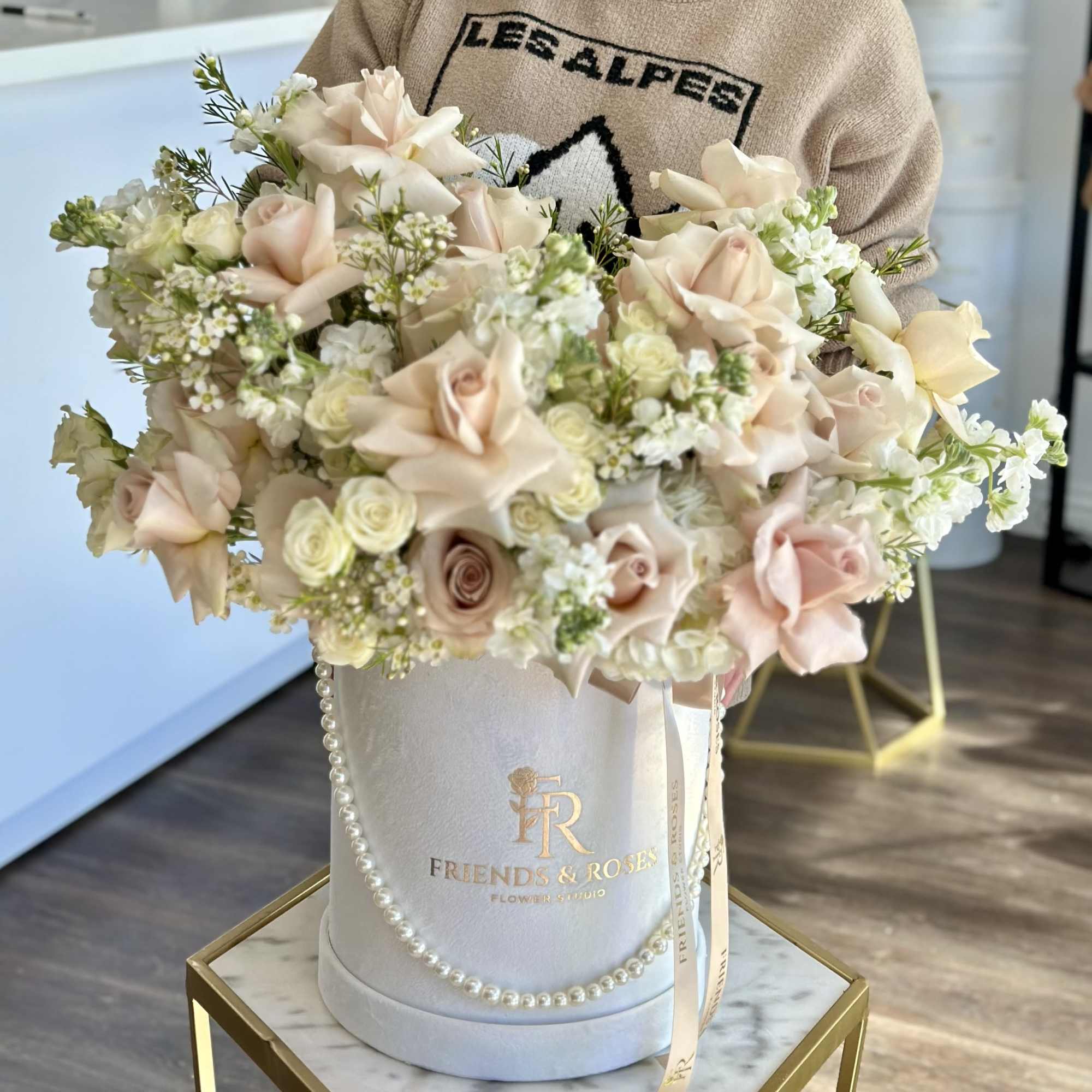 Blush and cream roses arranged in a white hatbox with pearl trim
