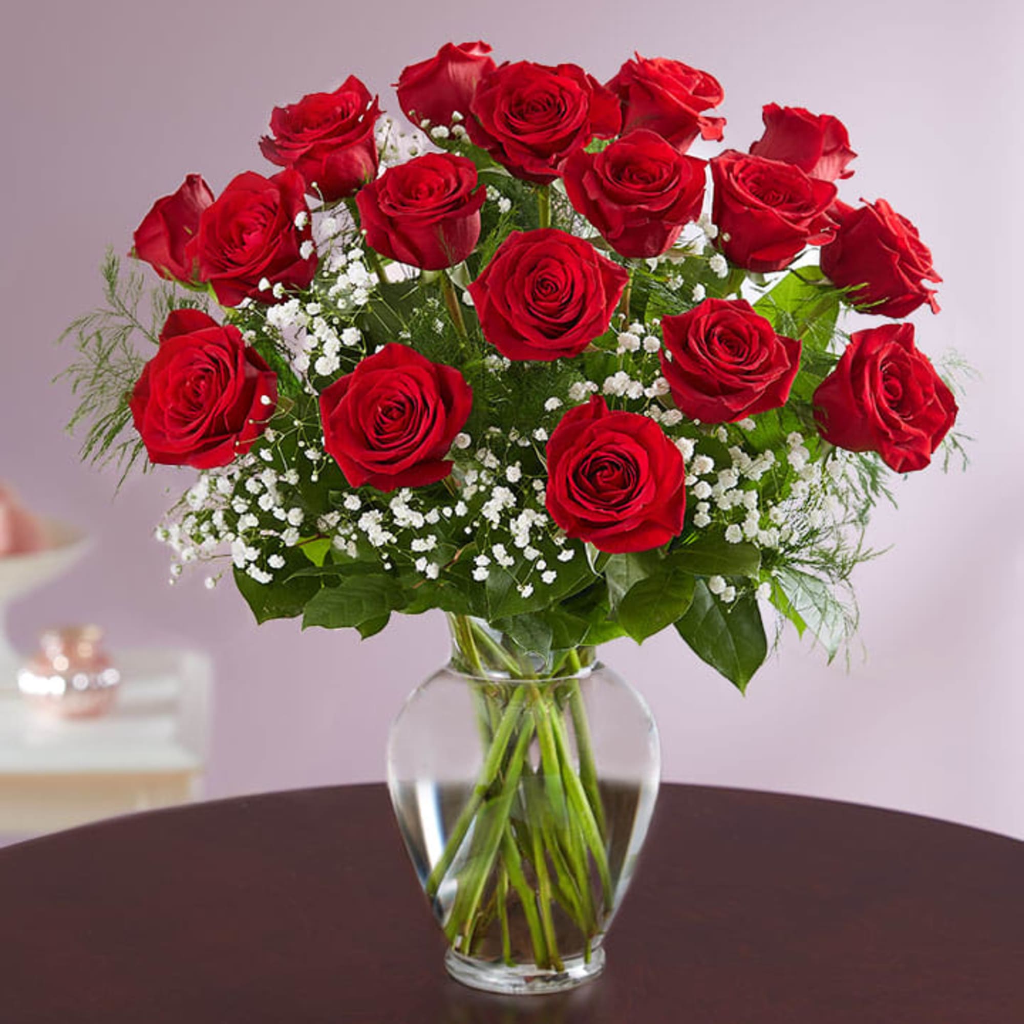 Red roses arranged in a clear glass vase with white filler flowers