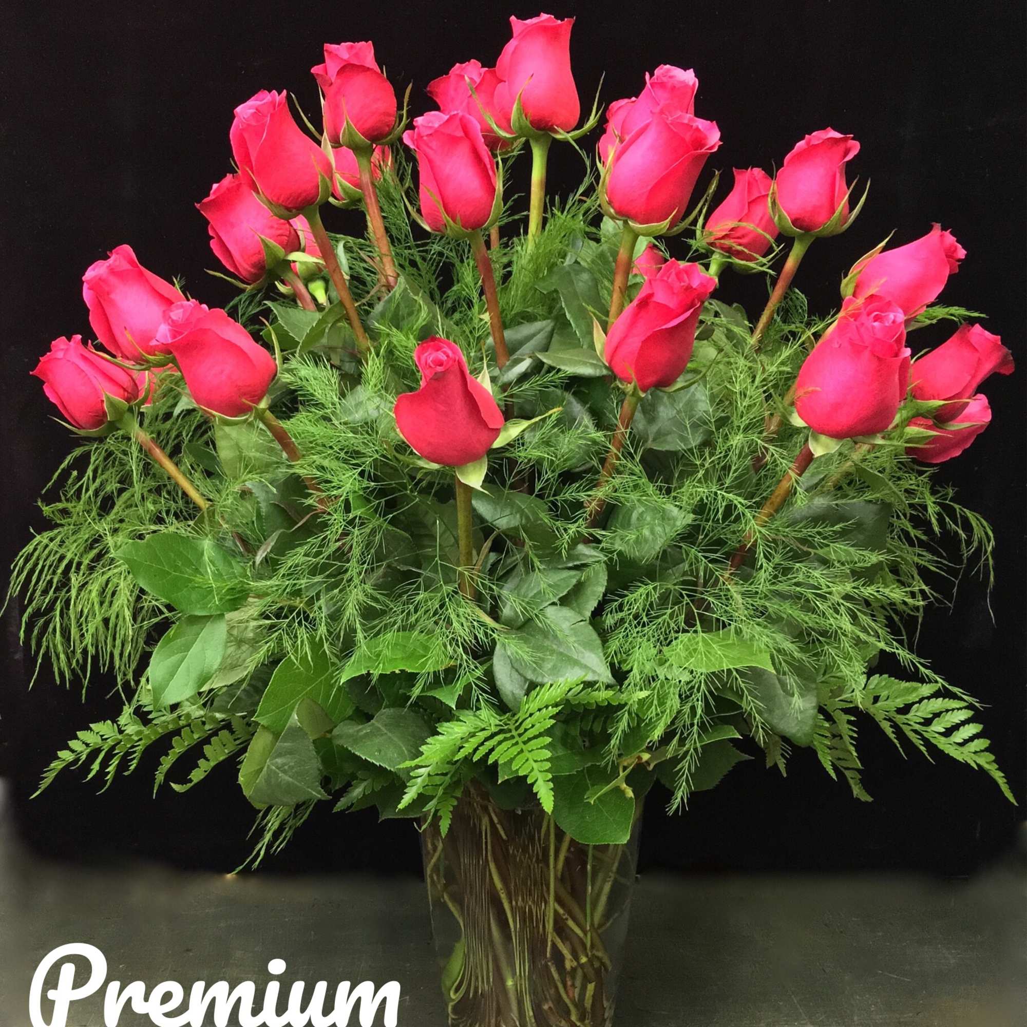 Pink roses arranged in a clear glass vase with greenery