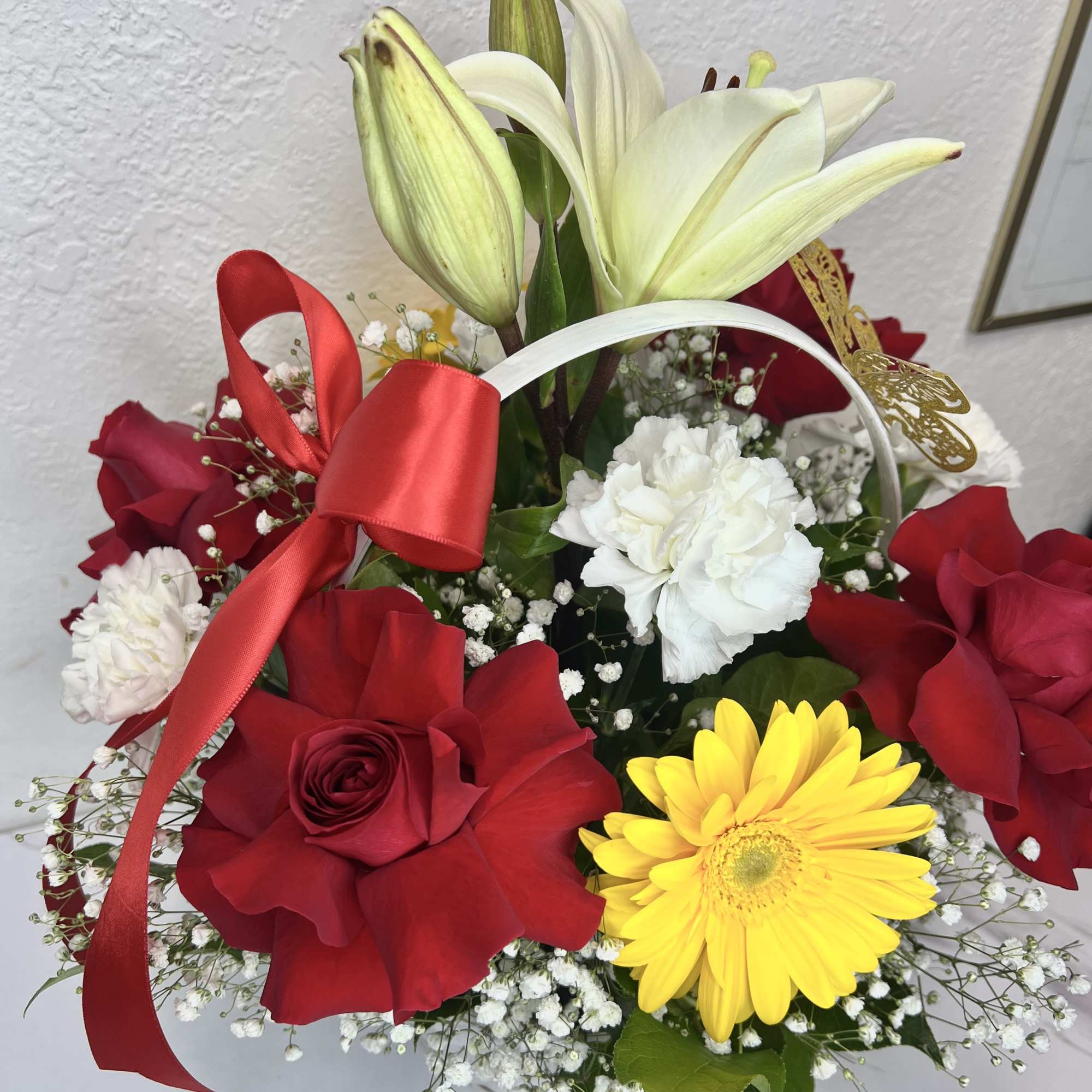 Bouquet of red roses, white lilies, and a yellow gerbera daisy with ribbon