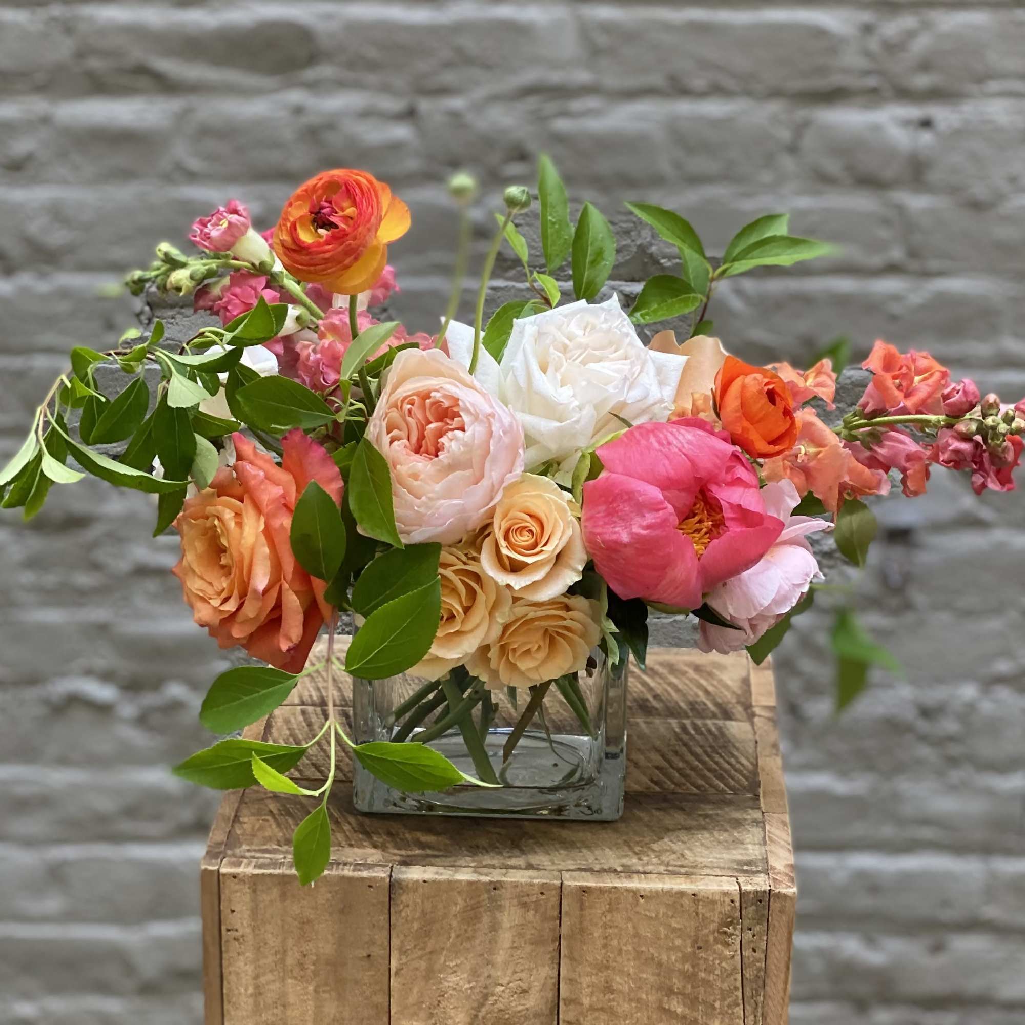 Mixed bouquet of pink, peach, white, and orange flowers in a glass vase
