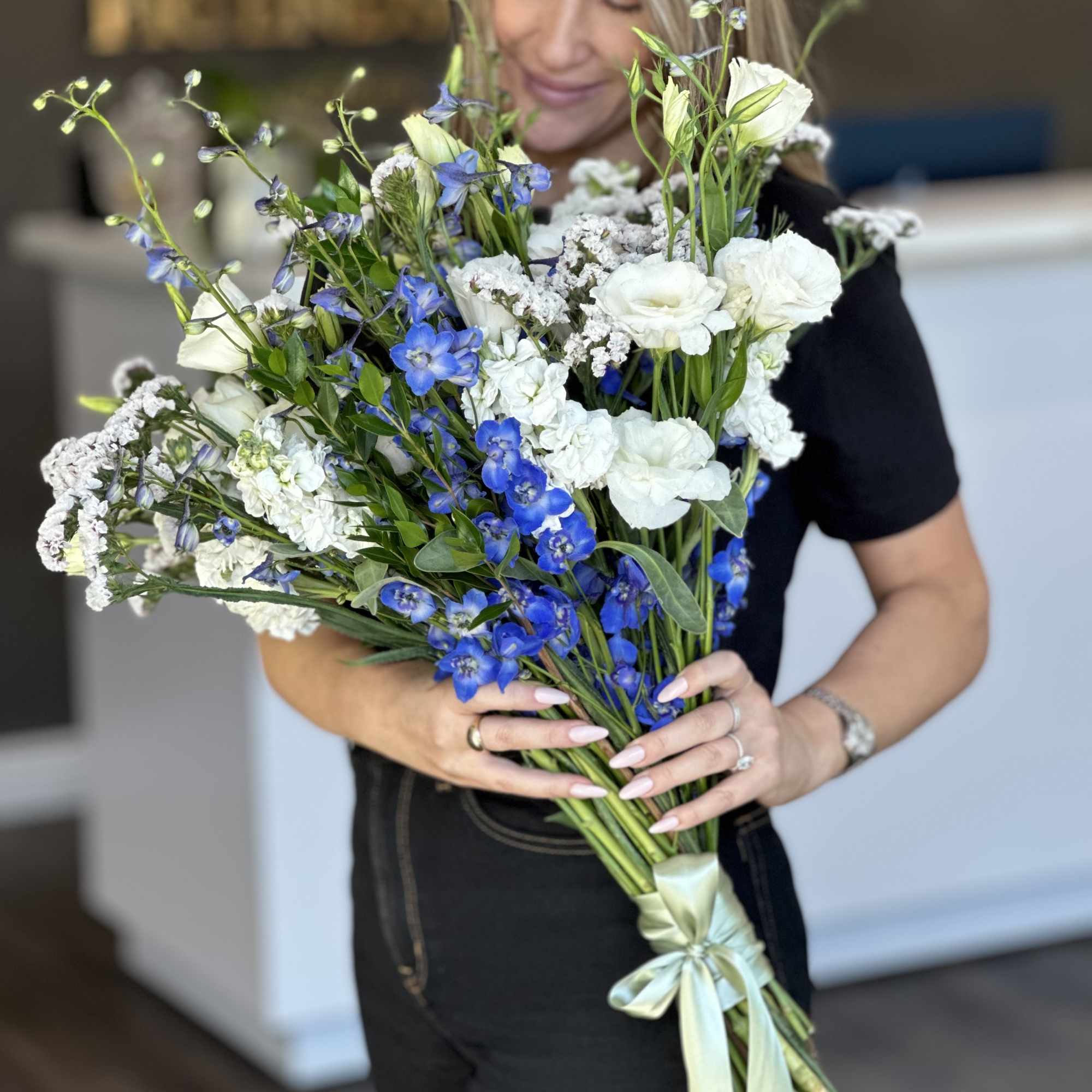 Handheld bouquet of white and blue flowers tied with a satin ribbon